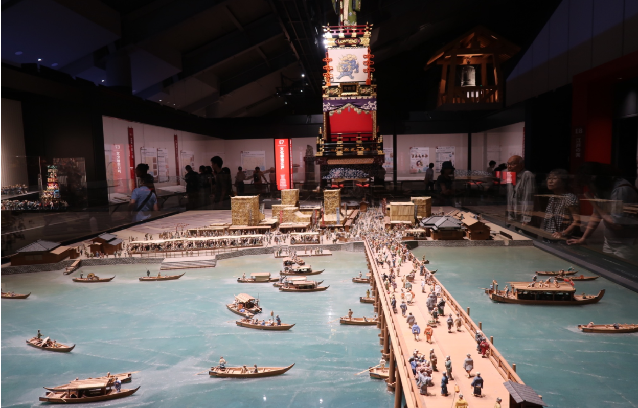 A miniature diorama of Edo Japan with boats passing under a boat.