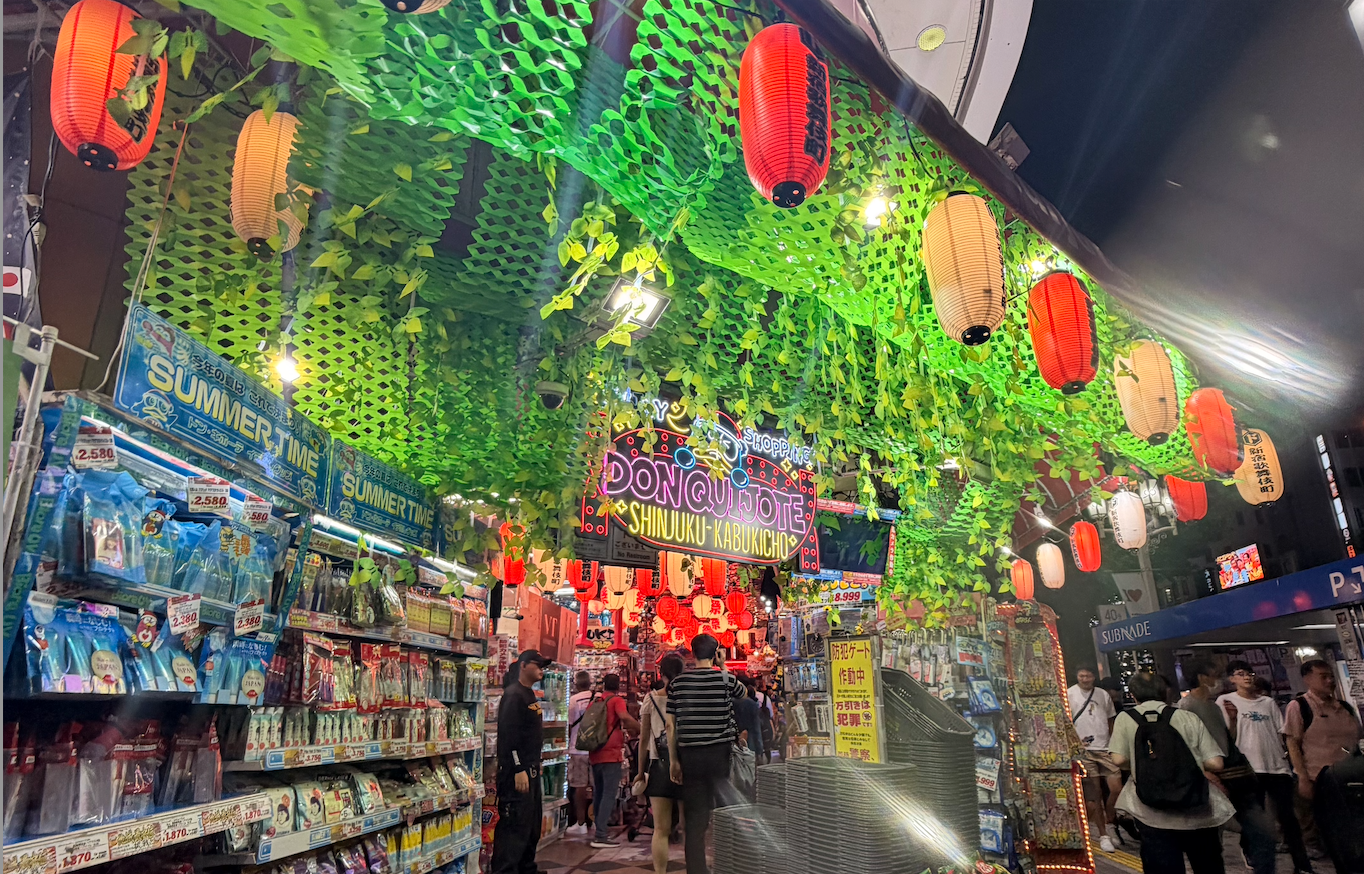 A vibrant entrance way of Don Quijote with green netting and lanterns.
