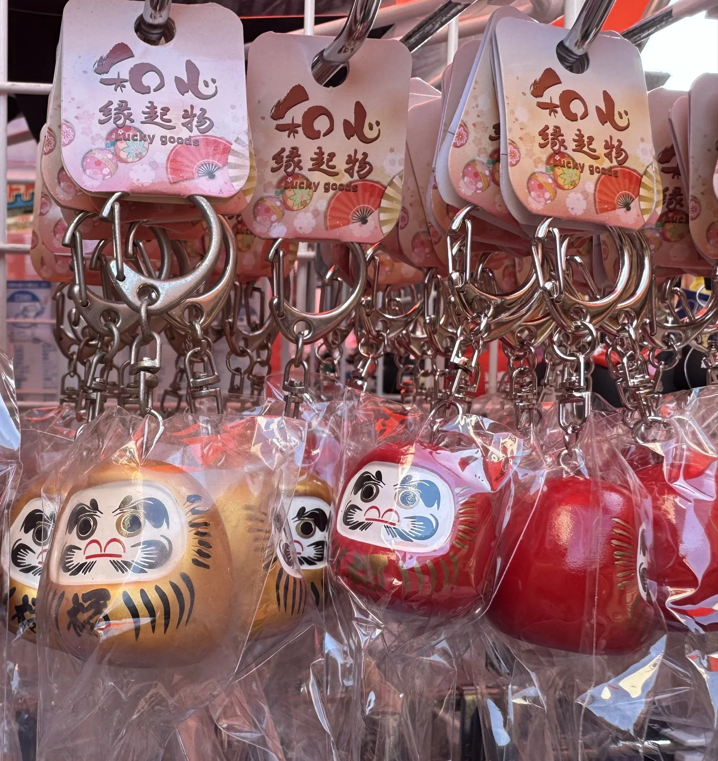 Japanese red daruma dolls with complete eyes and a small mustache. Dolls are on a keychain.