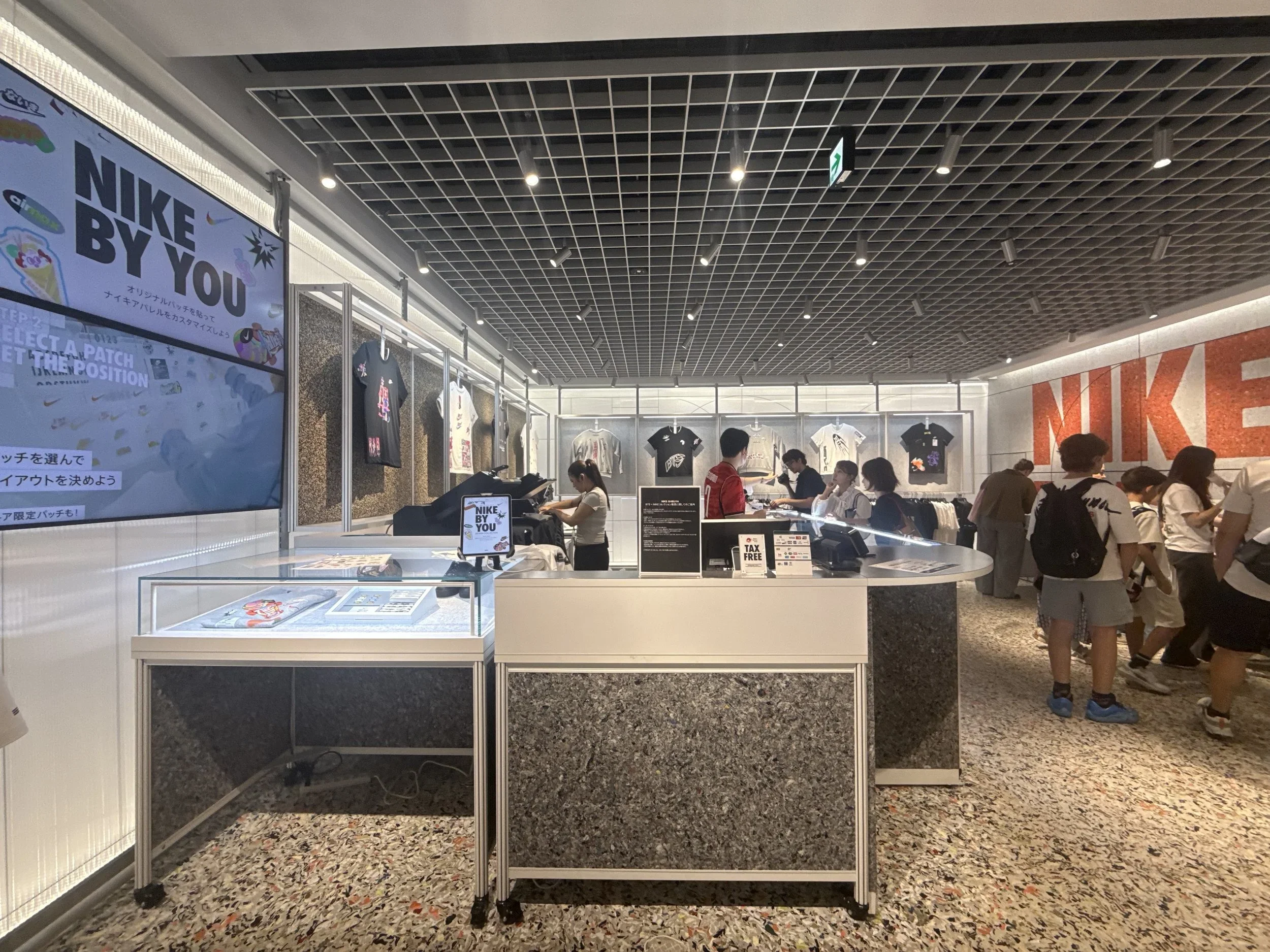 A Nike By You table in the Nike store, featuring glass display cases and tshirts handing on the wall.