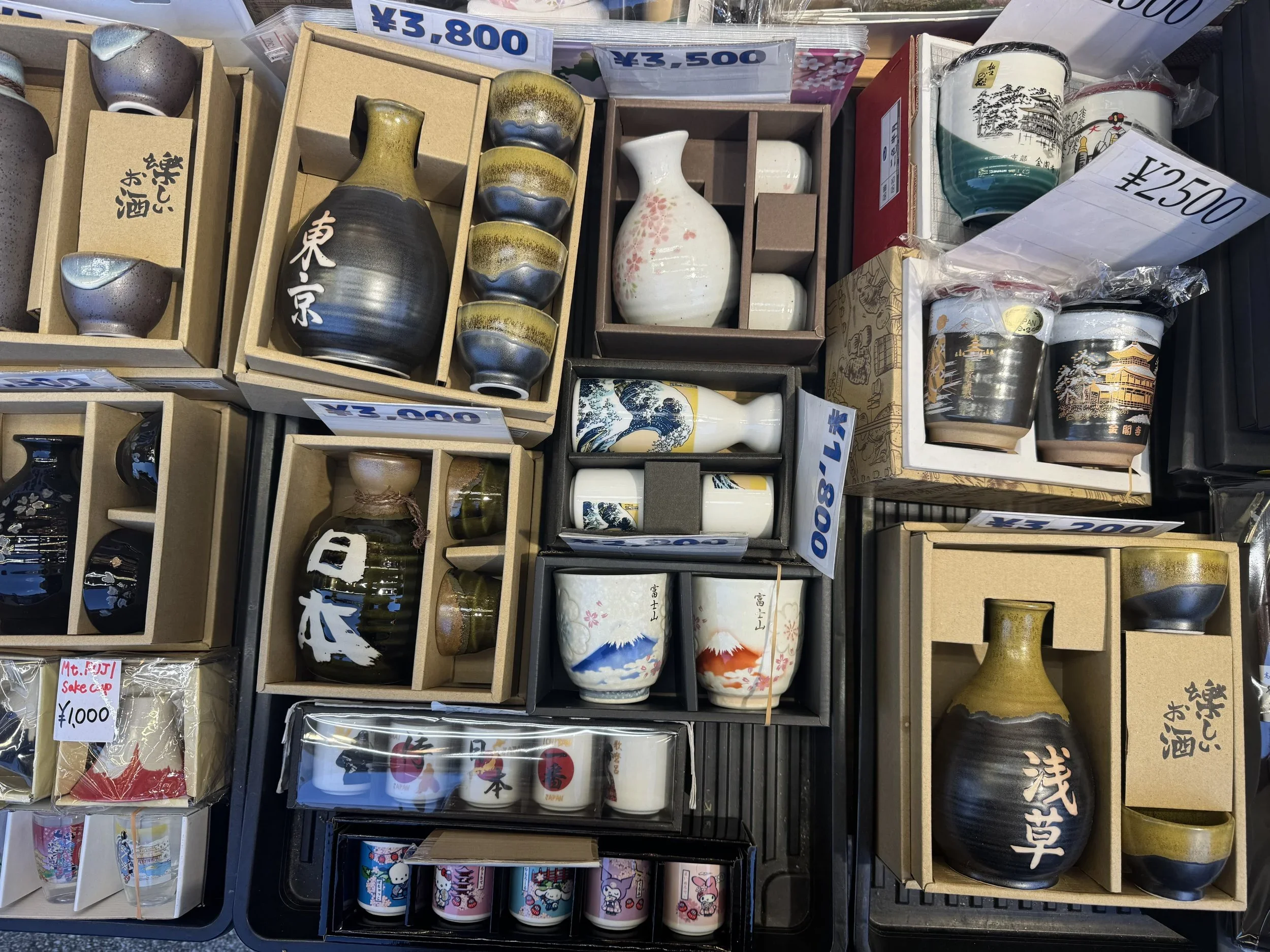 Sake cups and sake pitchers displayed in cardboard boxes at a antique market in Japan.
