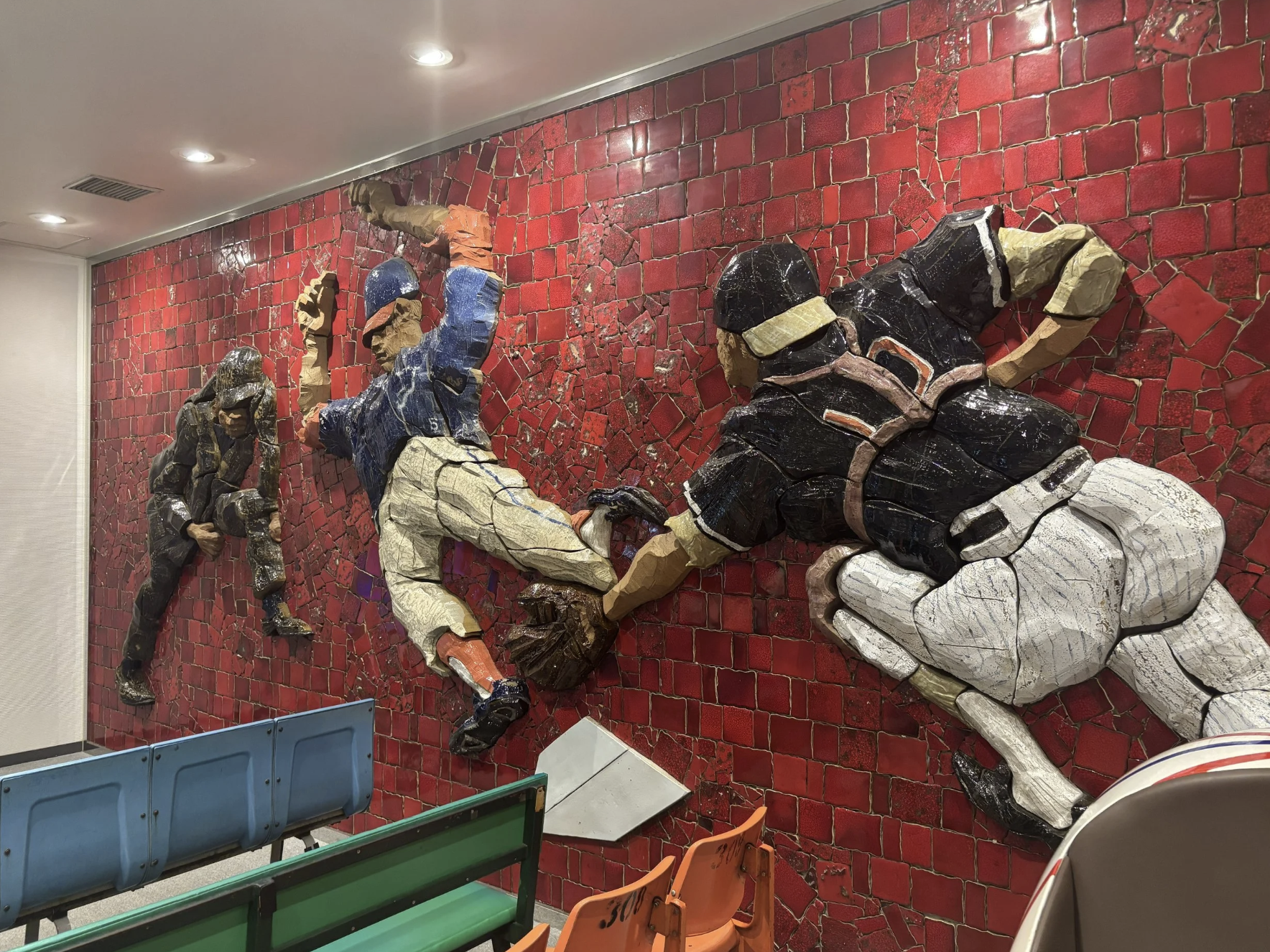 A 3D tile mural of a Baseball catcher tagging a player out on a wall in Tokyo Japan.