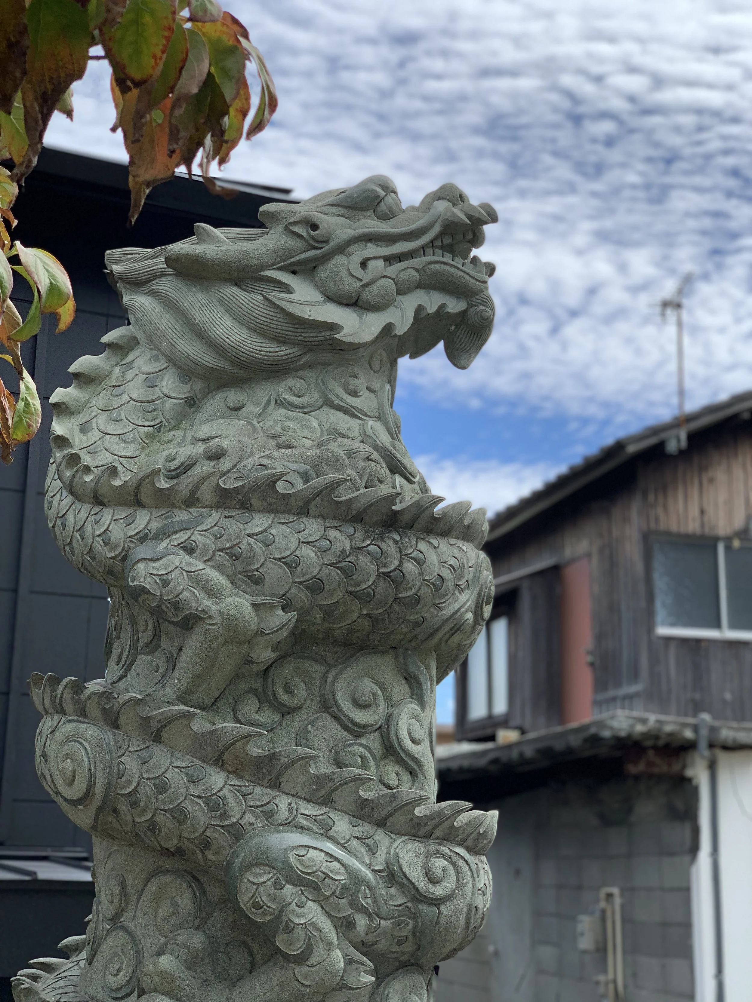 A stone lion loons up to a cloud filled blue sky looking towards the future with hope, just as your Japanese ancestors did.