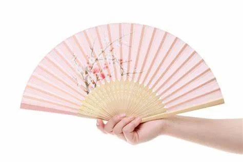 Pink Japanese fan with painted cherry blossoms held by a hand.