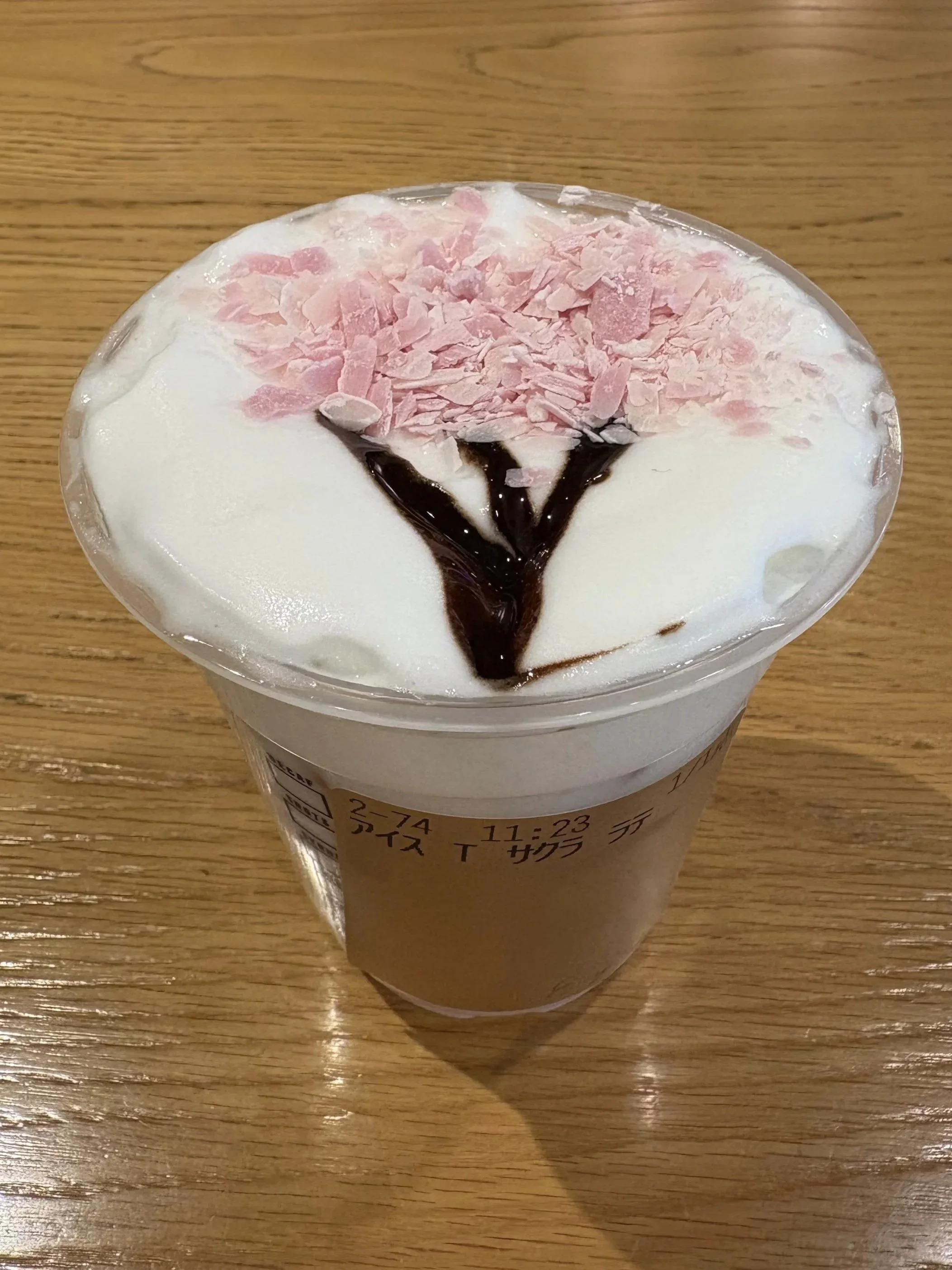 A tea with a cherry blossom tree on top made out of pink crumbled chocolate and chocolate syrup for the base and a white foam underneath.