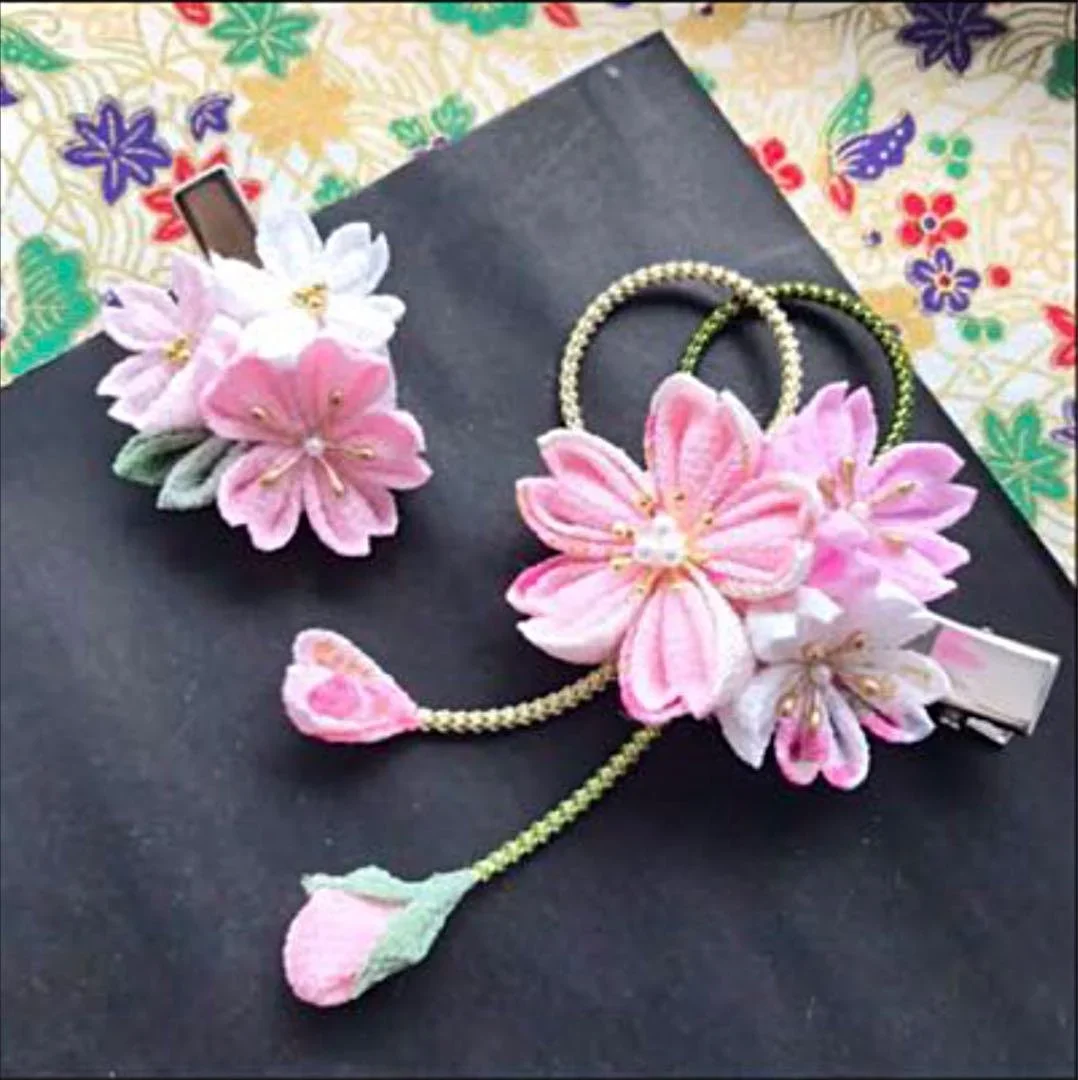 A pink hair accessory of folded fabric folded into a cherry blossom shape of several blossoms.