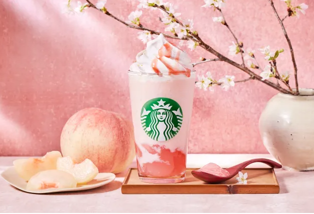 Starbucks cherry blossom drink with a peach and a cherry blossom branch next to it.