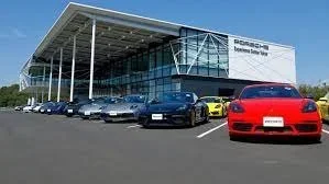 Porche cars parked outside of a contemporary glass and white material building.
