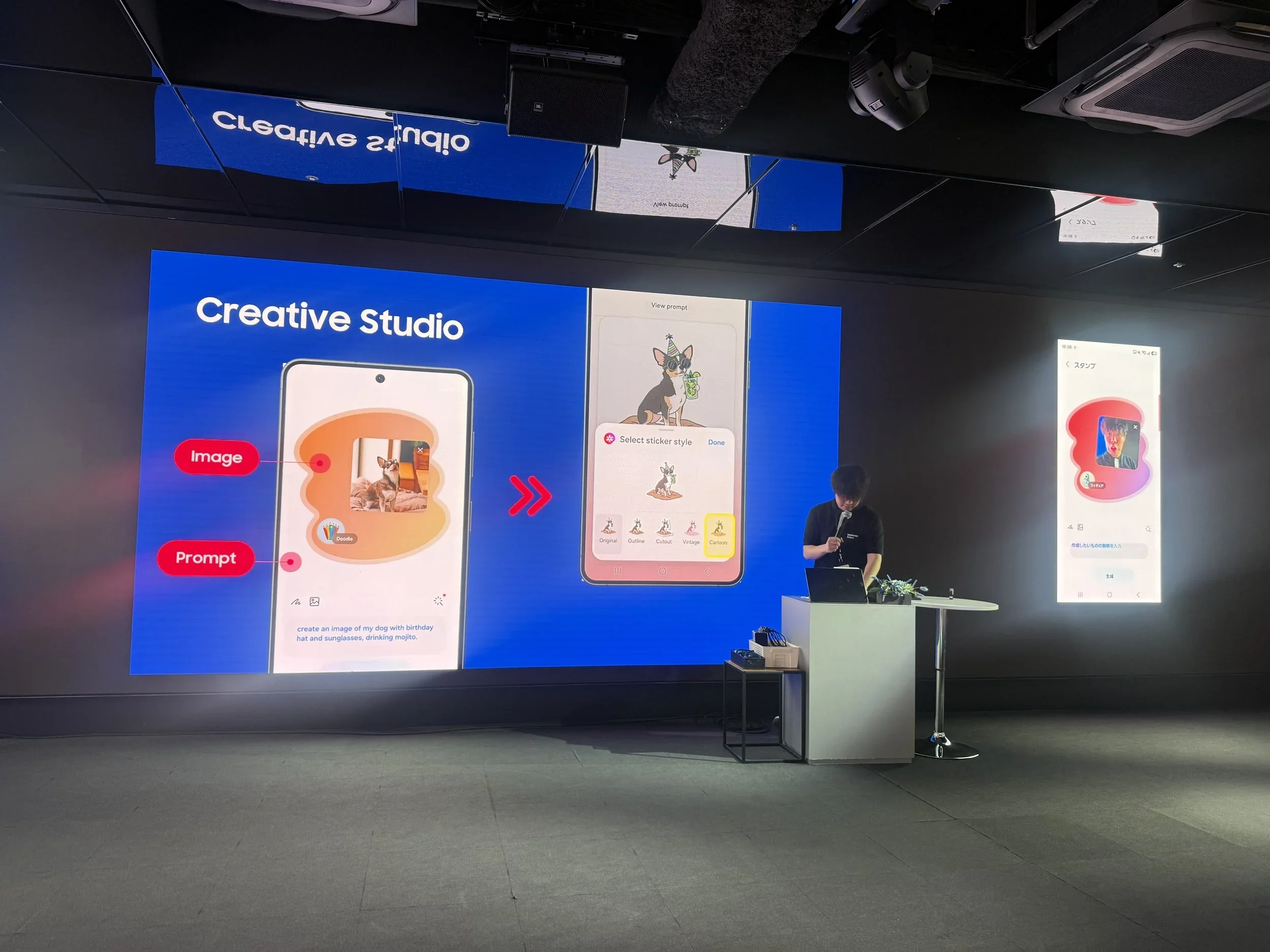 A presentation space in a black room with a blue powerpoint being presented showing a creative studio software from Samsung Galaxy.