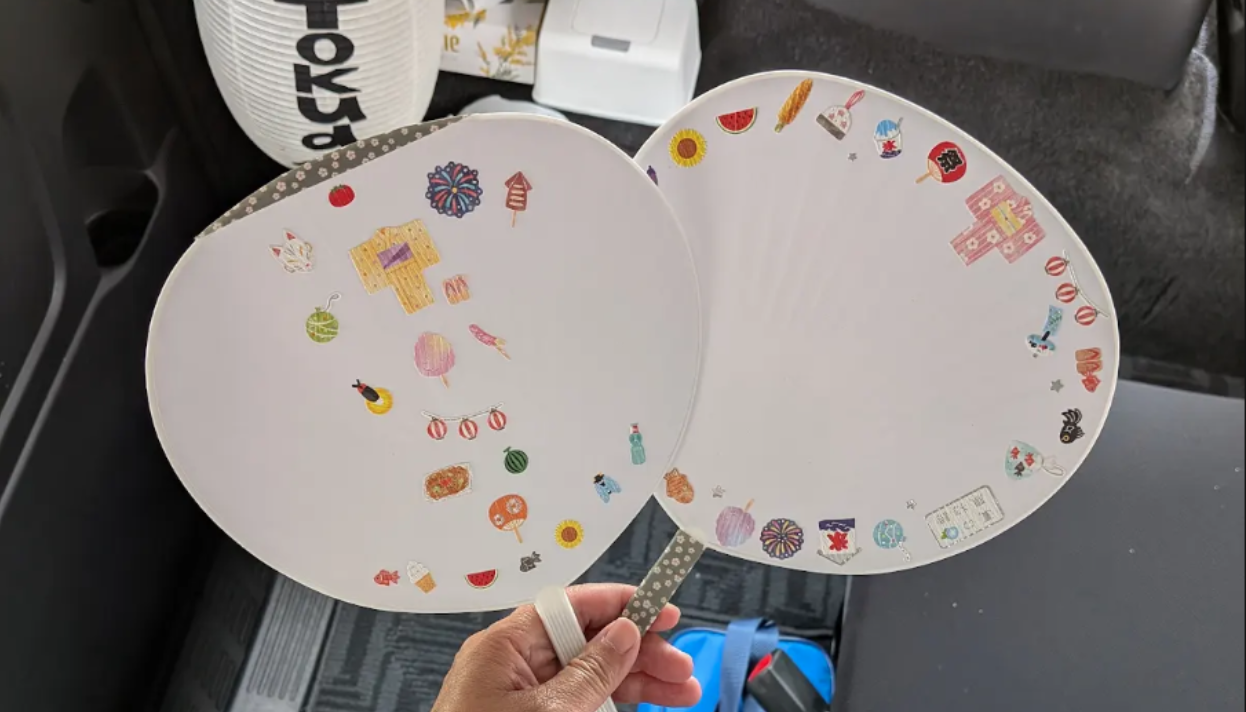 TokudAw guests decorate summer fans with stickers on them.