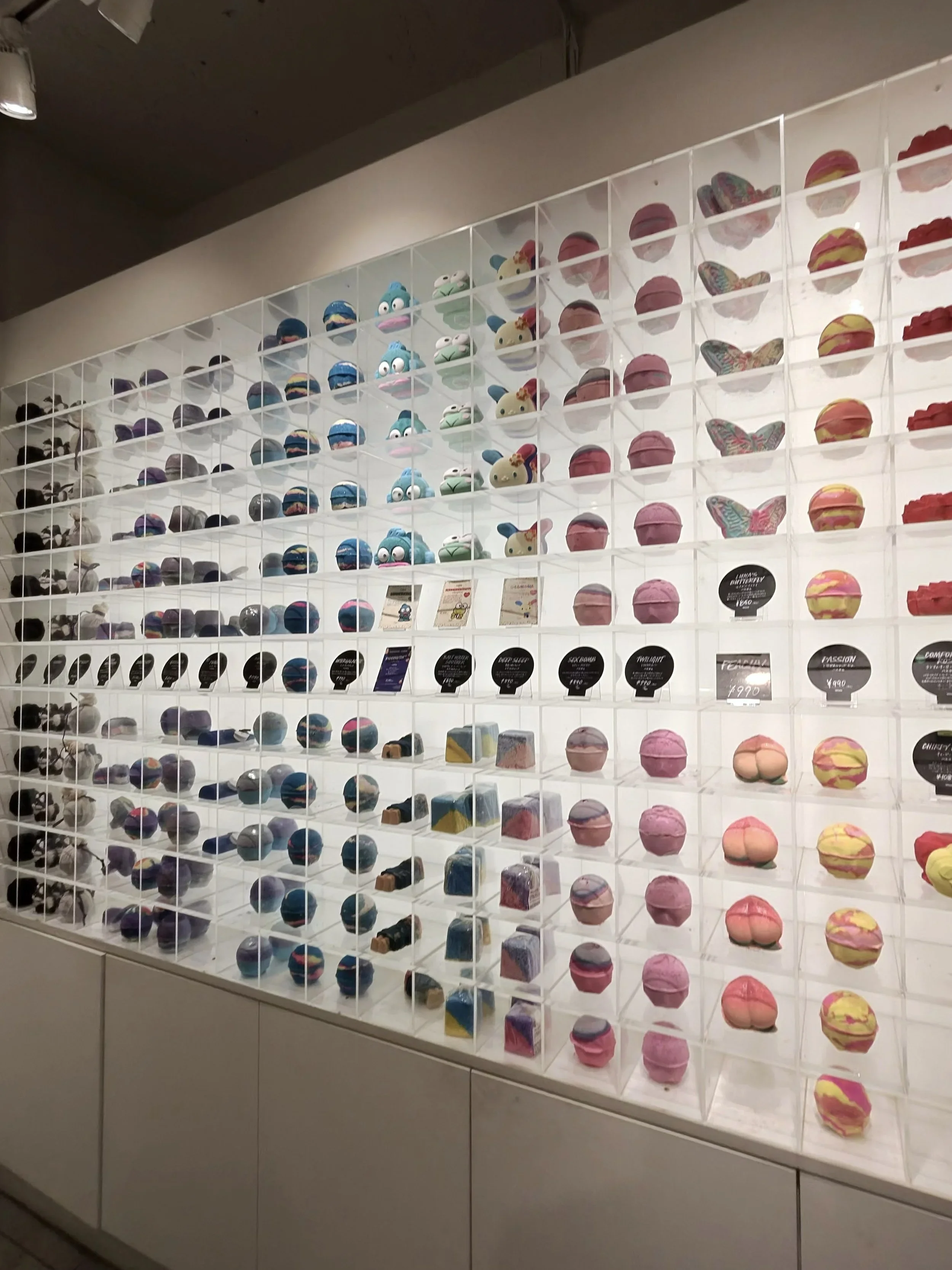 A colorful wall of handmade bath bombs and bath products at the Lush flagship store in Harajuku Tokyo, showcasing the brand's wide variety of scents, colors, and playful designs.