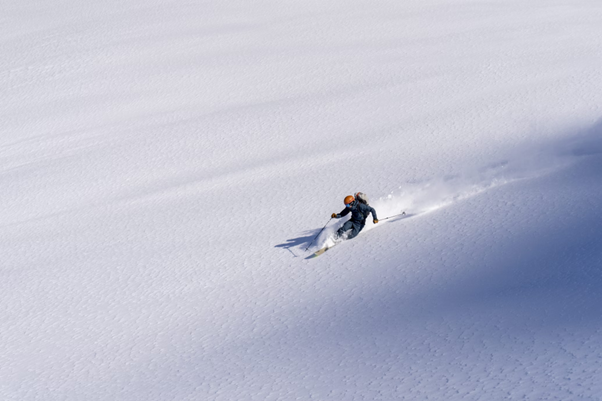 Skier makes their way through the Japanese powder snow with fresh tracks, no one in sight, and no trees around.
