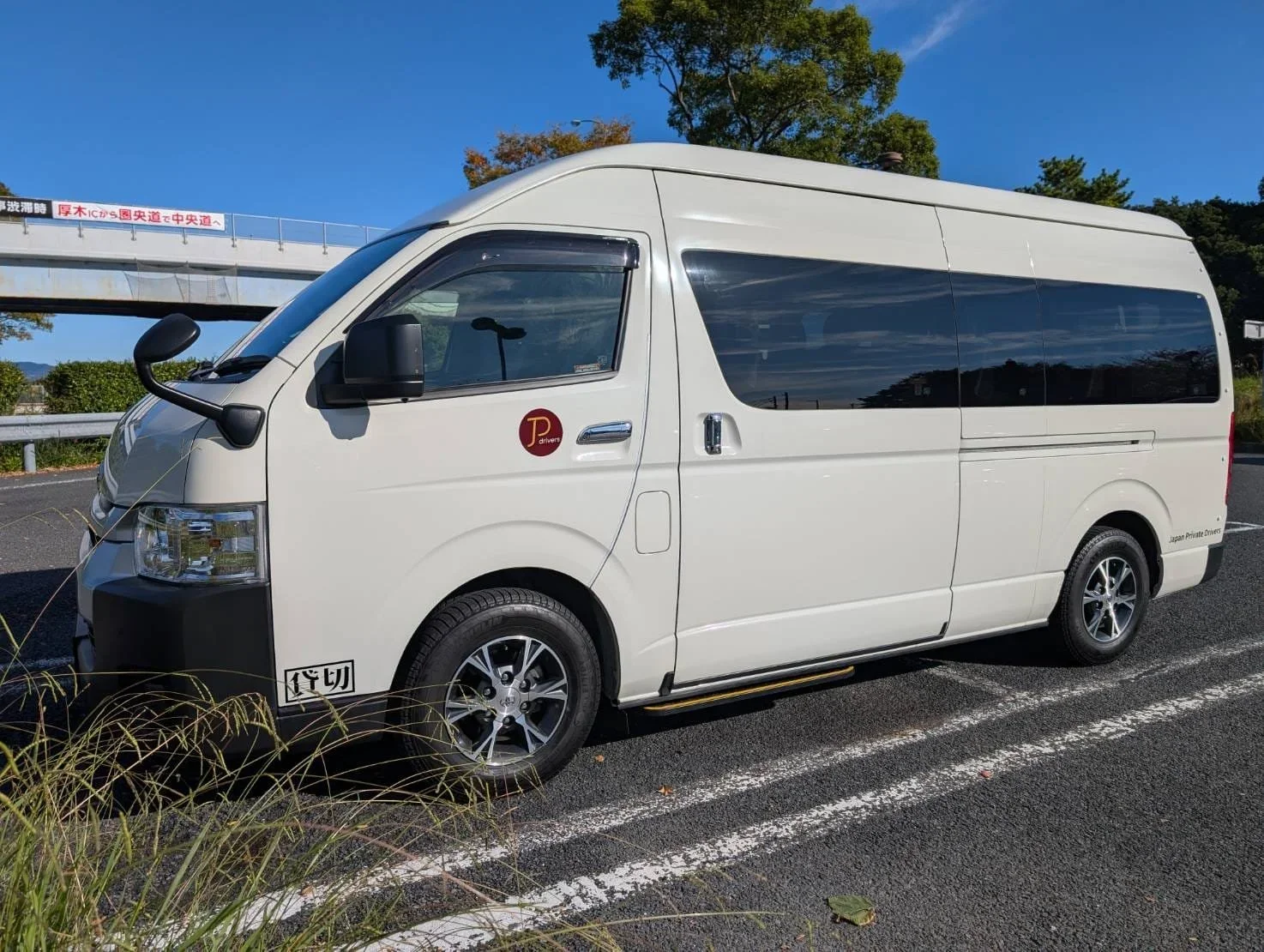 A white van parked in a parking lot with the Japan Private Drivers sticker.