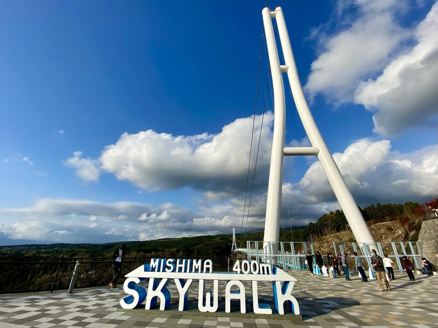 The entrance to a pedestrian bridge known as Mishima Sky walk on a cloudy day with blue skies.