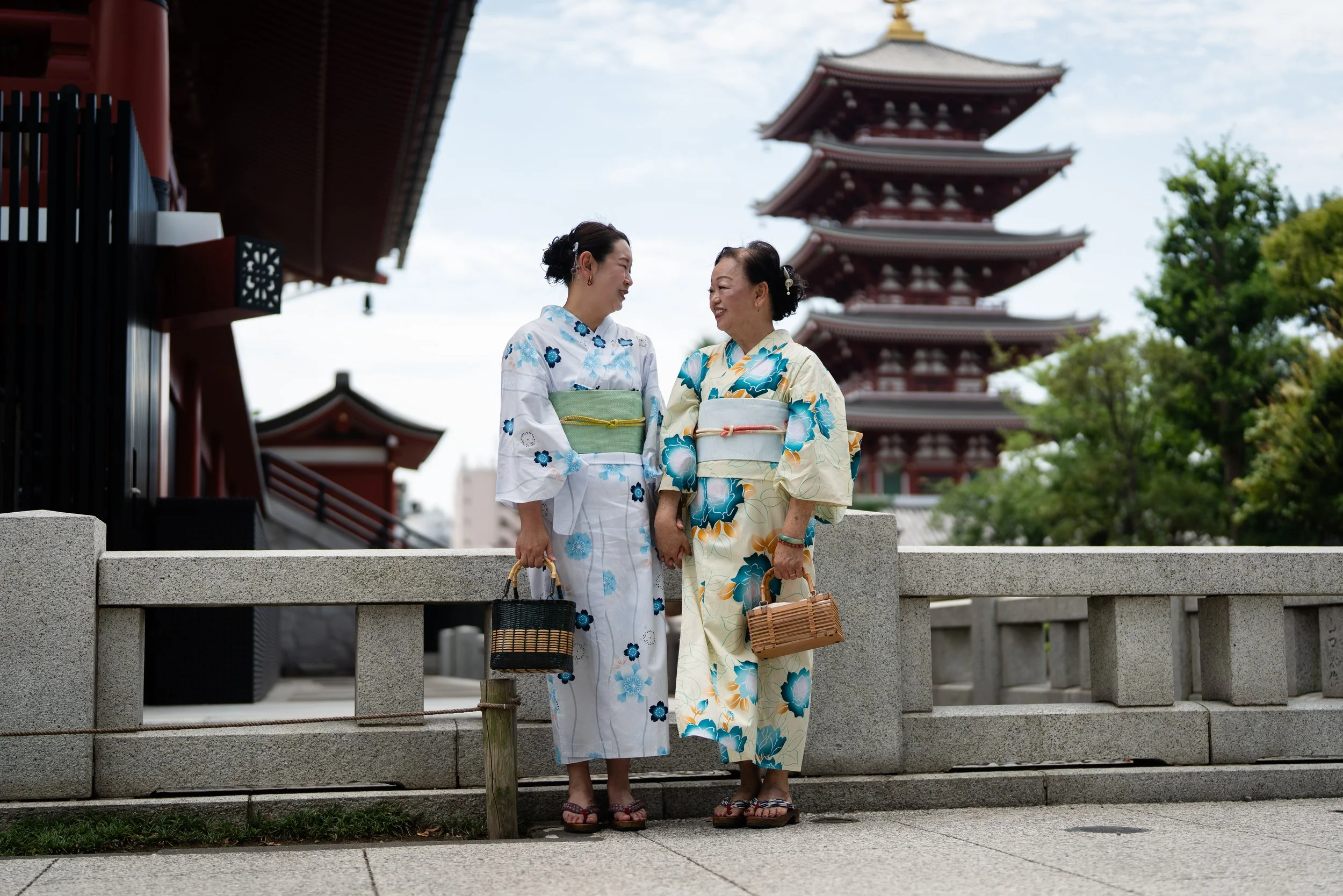 A Daughter and a mother dressed in a traditional Japanese outfit or yukata with a japanese five story pagoda in the backdrop.
