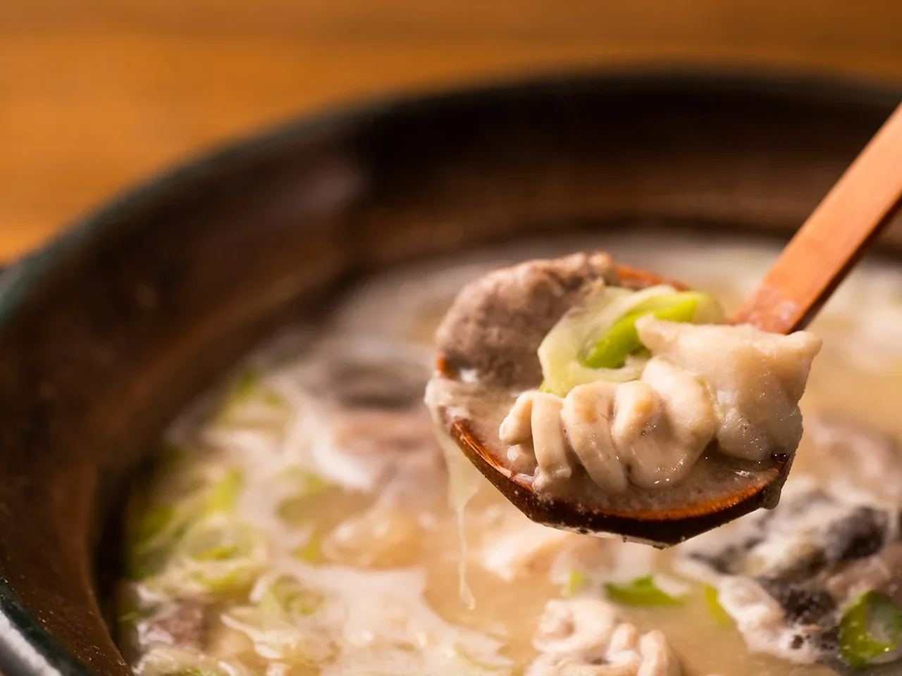 Dongara soup in a spoon positioned above a bowl.