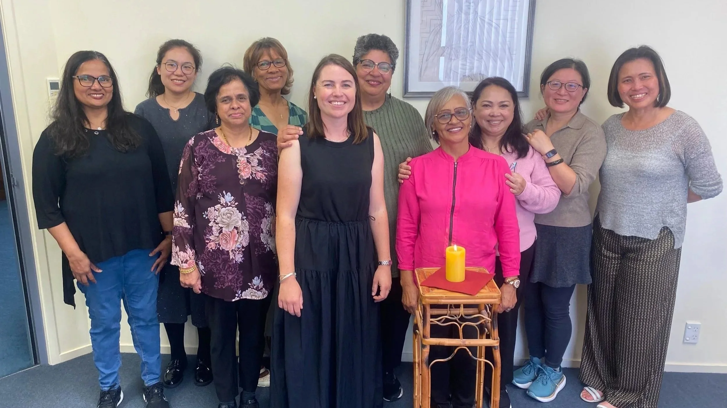 Marist Way group of women standing together smiling, with a candle on a small table in front of them.