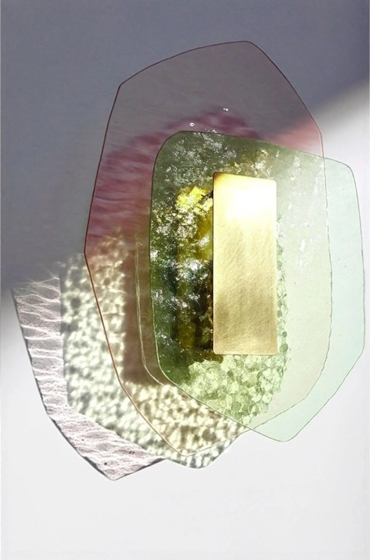 A multi-layered paper or acrylic art piece with a photograph of trees and sunlight, and a square gold element.