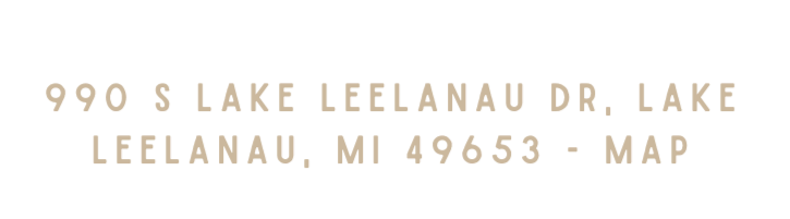 Text displaying the address '990 S Lake Leelanau Dr. Lake Leelanau, MI 49653 - Map' on a black background.