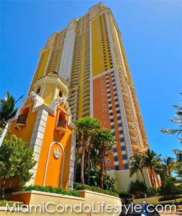 Tall, colorful residential building in Miami with tropical trees and clear blue sky