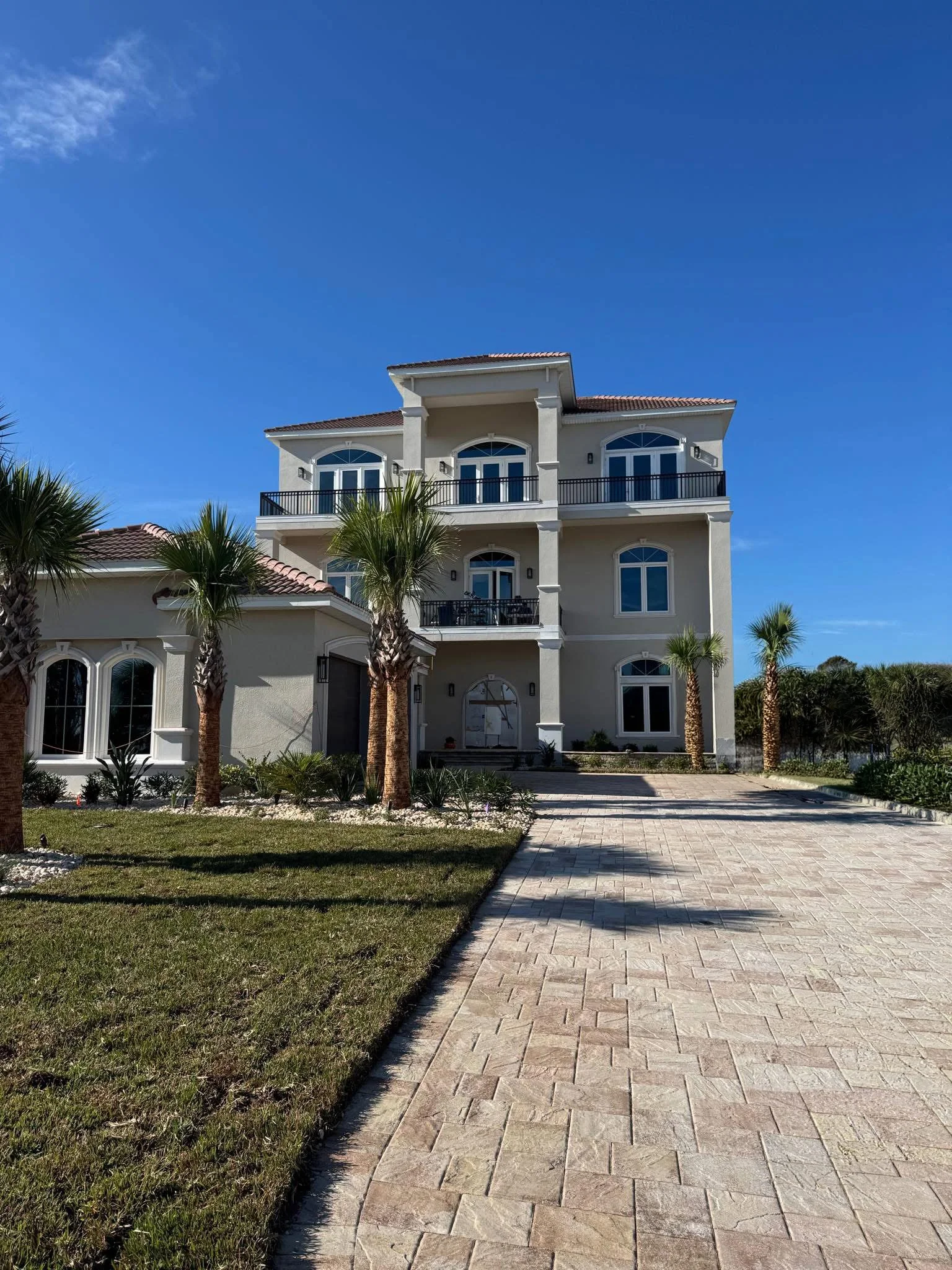 Arrive at an elegant Palm Coast vacation home framed by swaying palm trees, spacious balconies, and beautiful coastal architecture that immediately sets the tone for a luxurious Florida getaway.