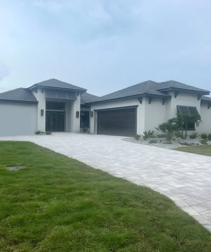 Front view of a modern two-story house with a gray roof, white exterior walls, a front porch, and a driveway leading to a garage.