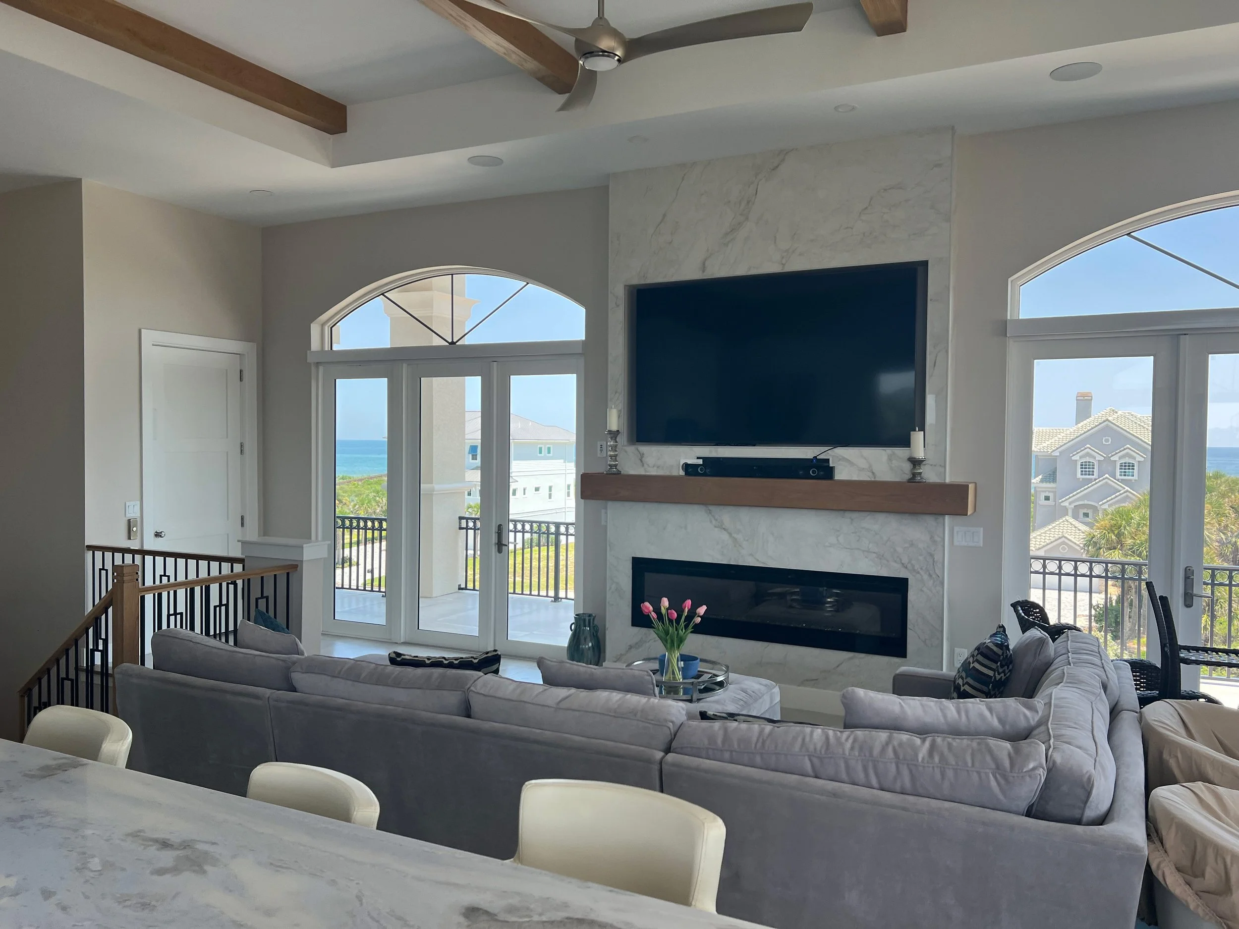 Settle into a bright, comfortable living room where ocean views, soft coastal touches, a cozy fireplace, and plenty of space make it easy to relax and enjoy time together after a day in Palm Coast.