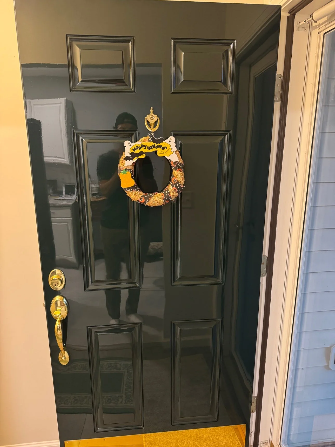 Entry door refinished in black high gloss, exterior face, with polished brass door knocker and kick plate