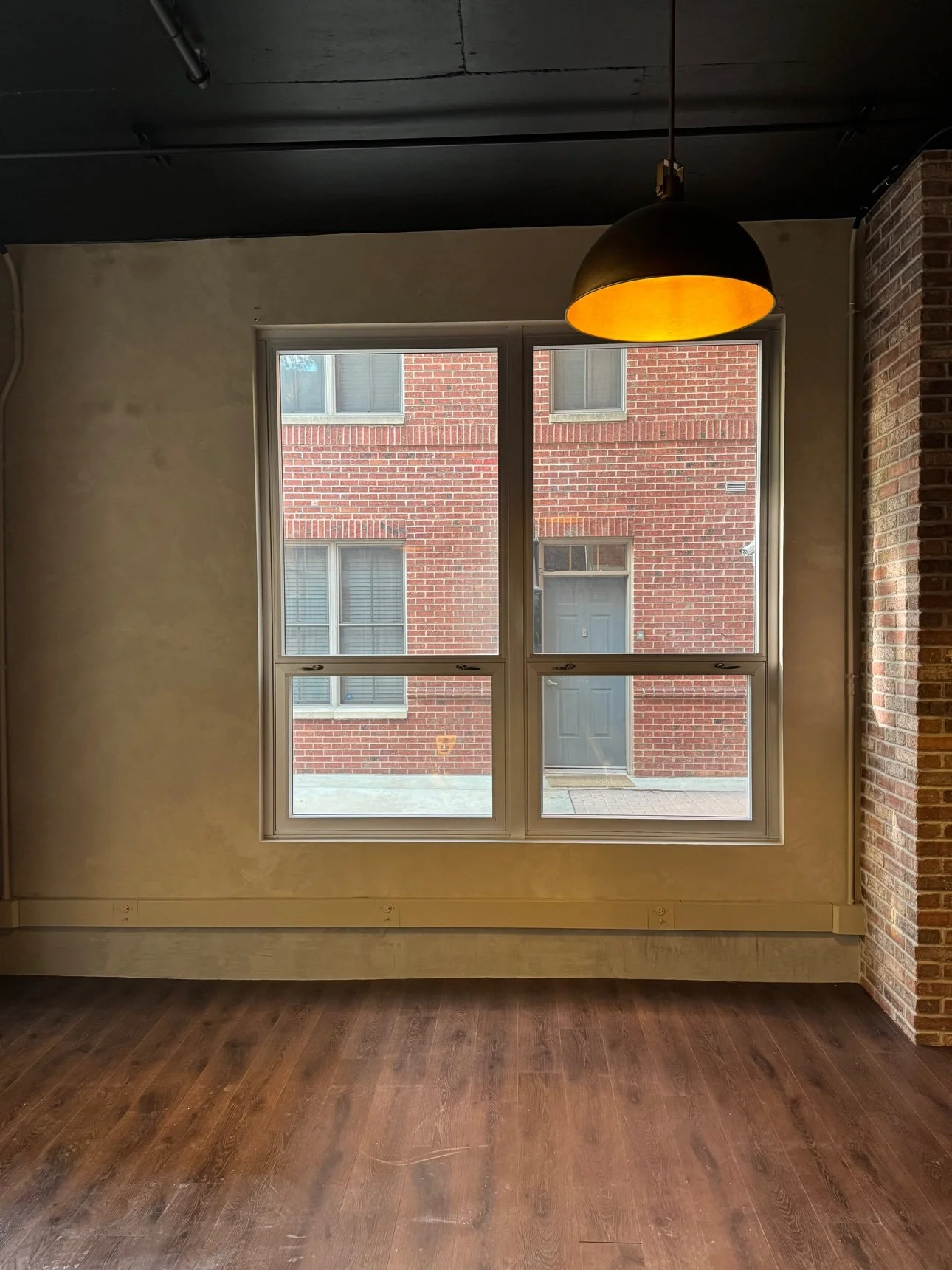Warm plaster wall with tall windows and a pendant lamp in a commercial event space, seen straight on