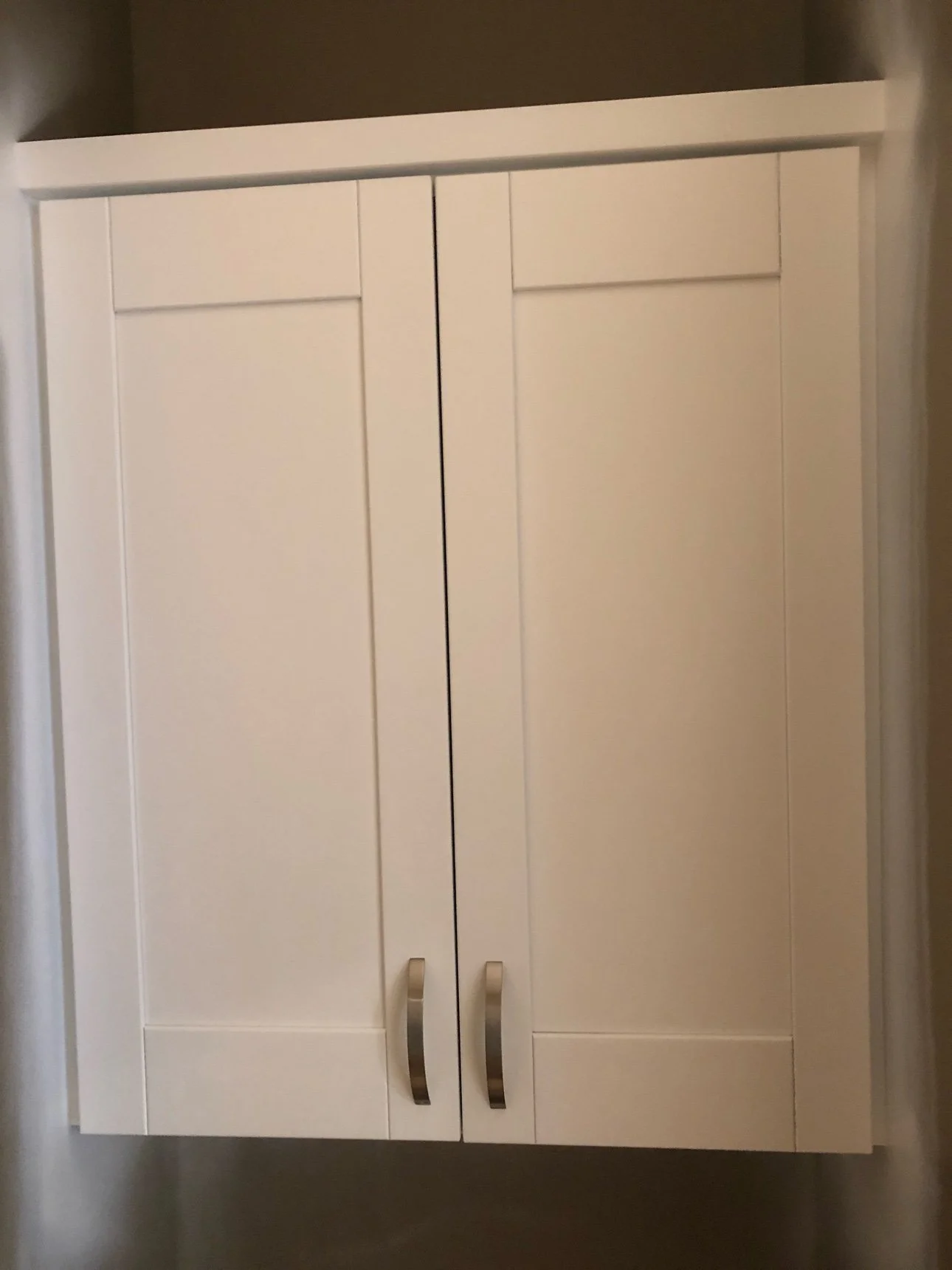 Finished white shaker double cabinet with brushed-nickel pulls, close detail