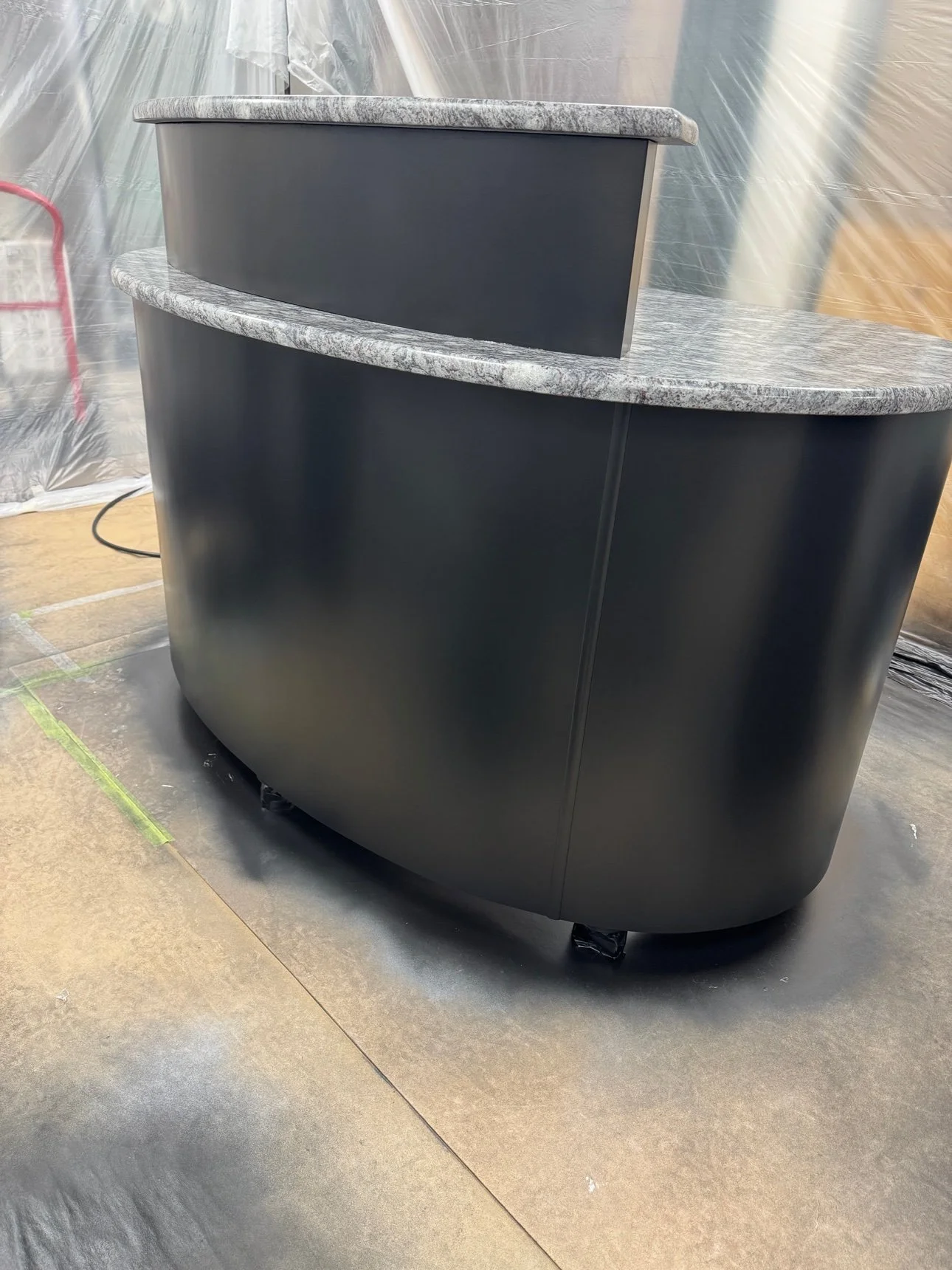 Curved reception desk refinished in matte black with granite counters