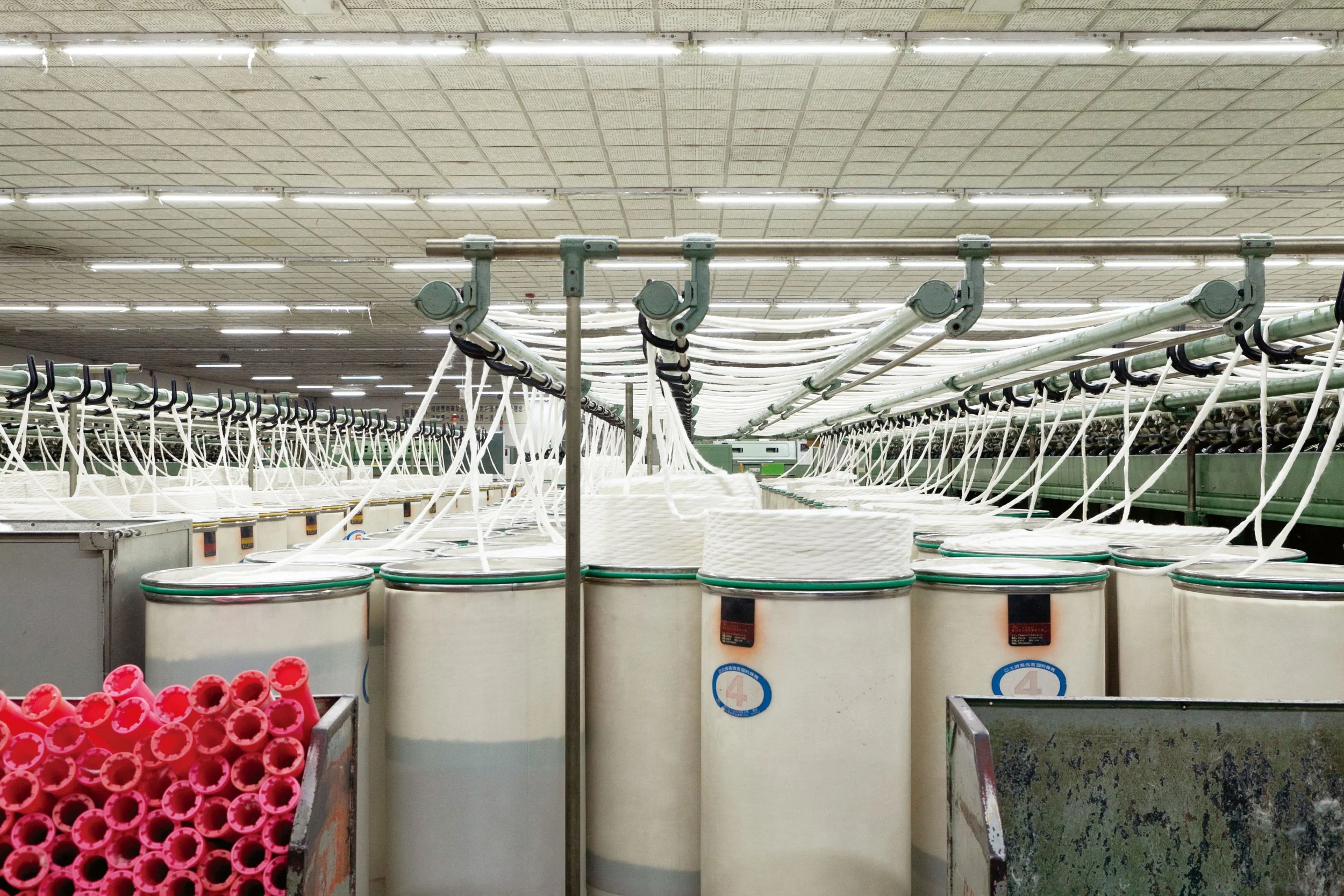 UCHINO Towel yarn making Factory. large white cylindrical tanks connected by pipes and hoses, with red plastic caps or containers in the foreground.