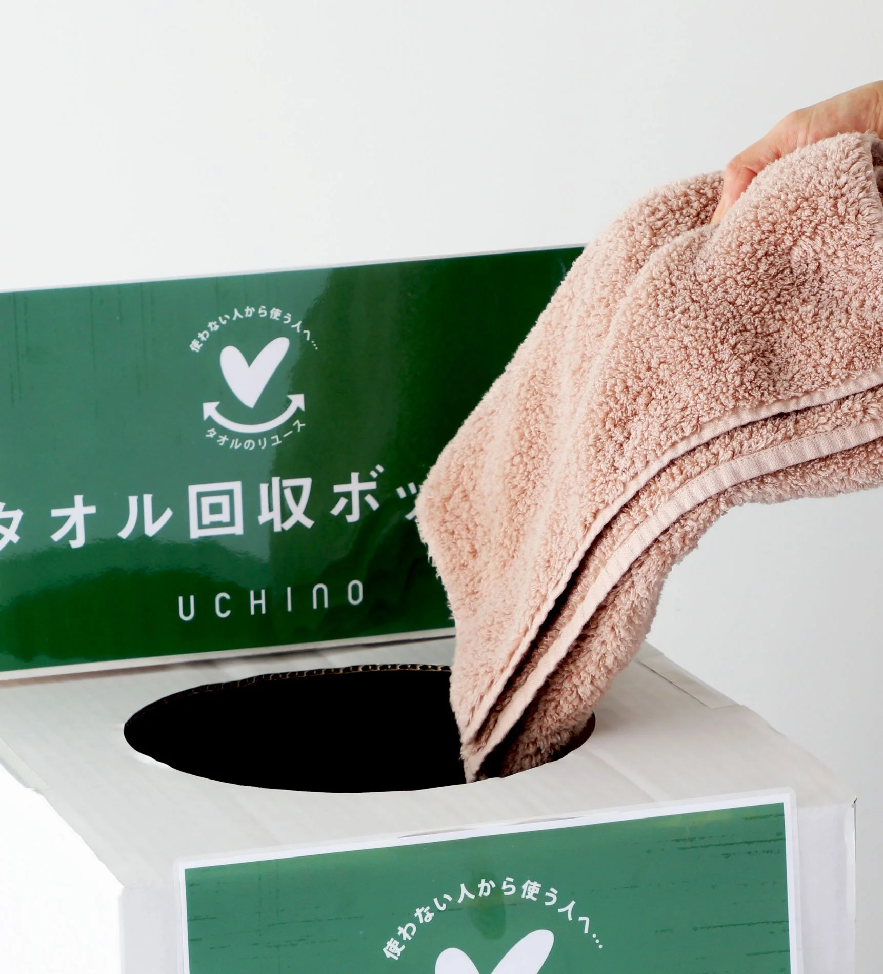 Towel Recycle campaign by UCHINO. green recycling bin with Japanese writing and a white heart symbol.
