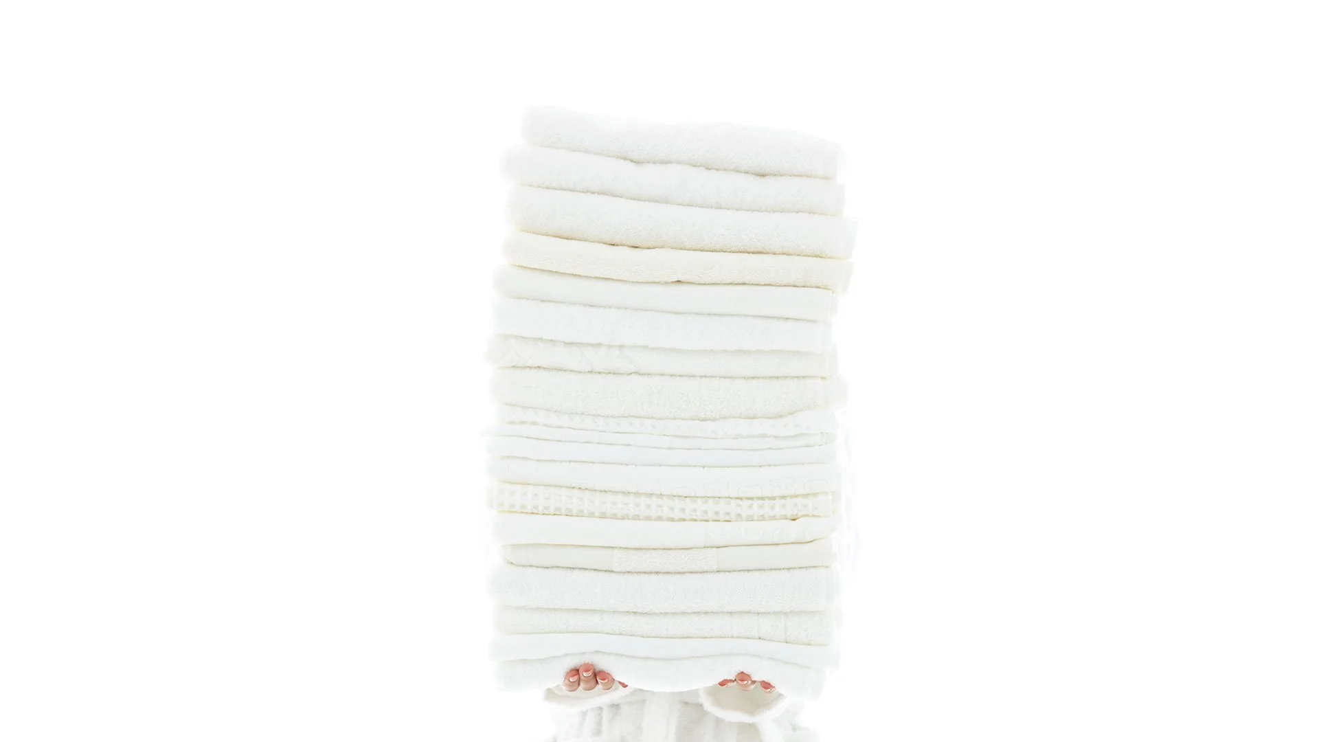 Stack of folded UCHINO white towels on white background.