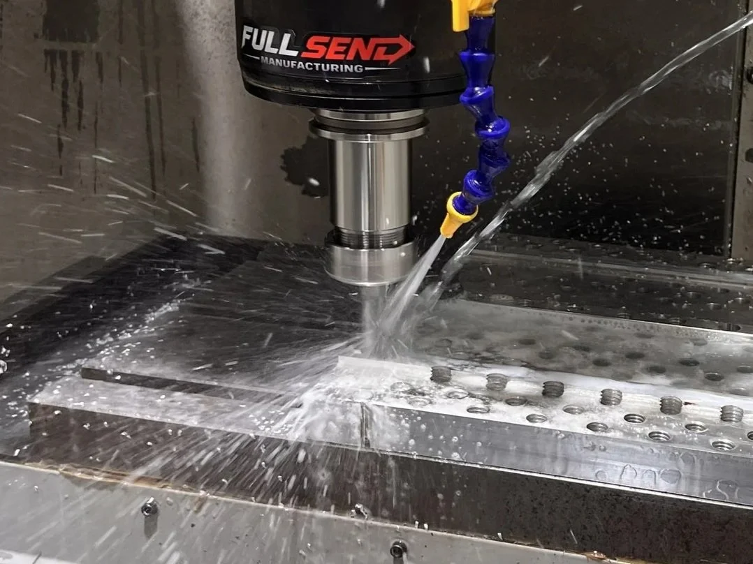 A milling machine cutting a metal workpiece with coolant spray.