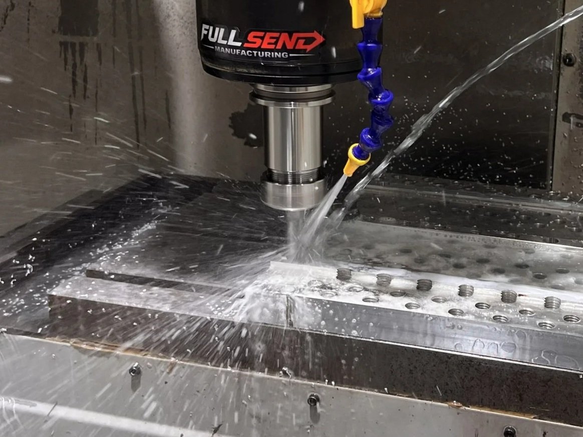 A CNC machine milling a metal workpiece with coolant being sprayed onto it.