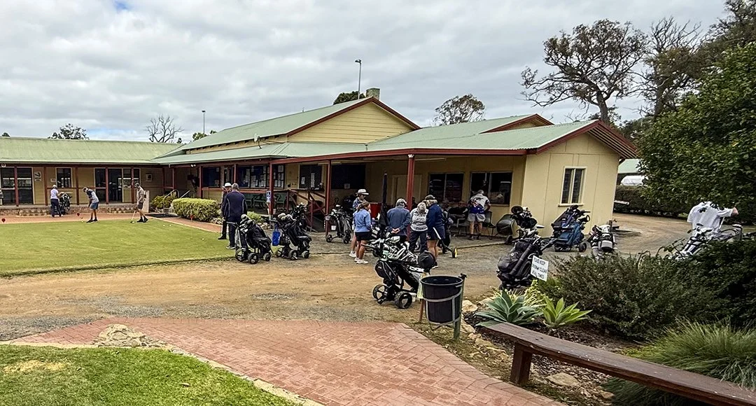 Golfers gather outside Donnybrook clubhouse with golf carts parked nearby on a partly cloudy day.
