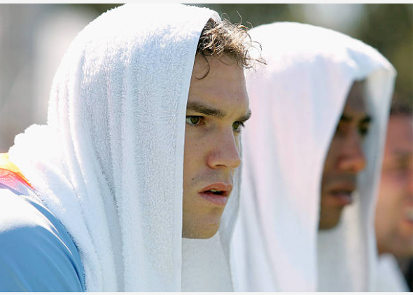 Three athletes with towels on their heads, focusing in a sporting event.