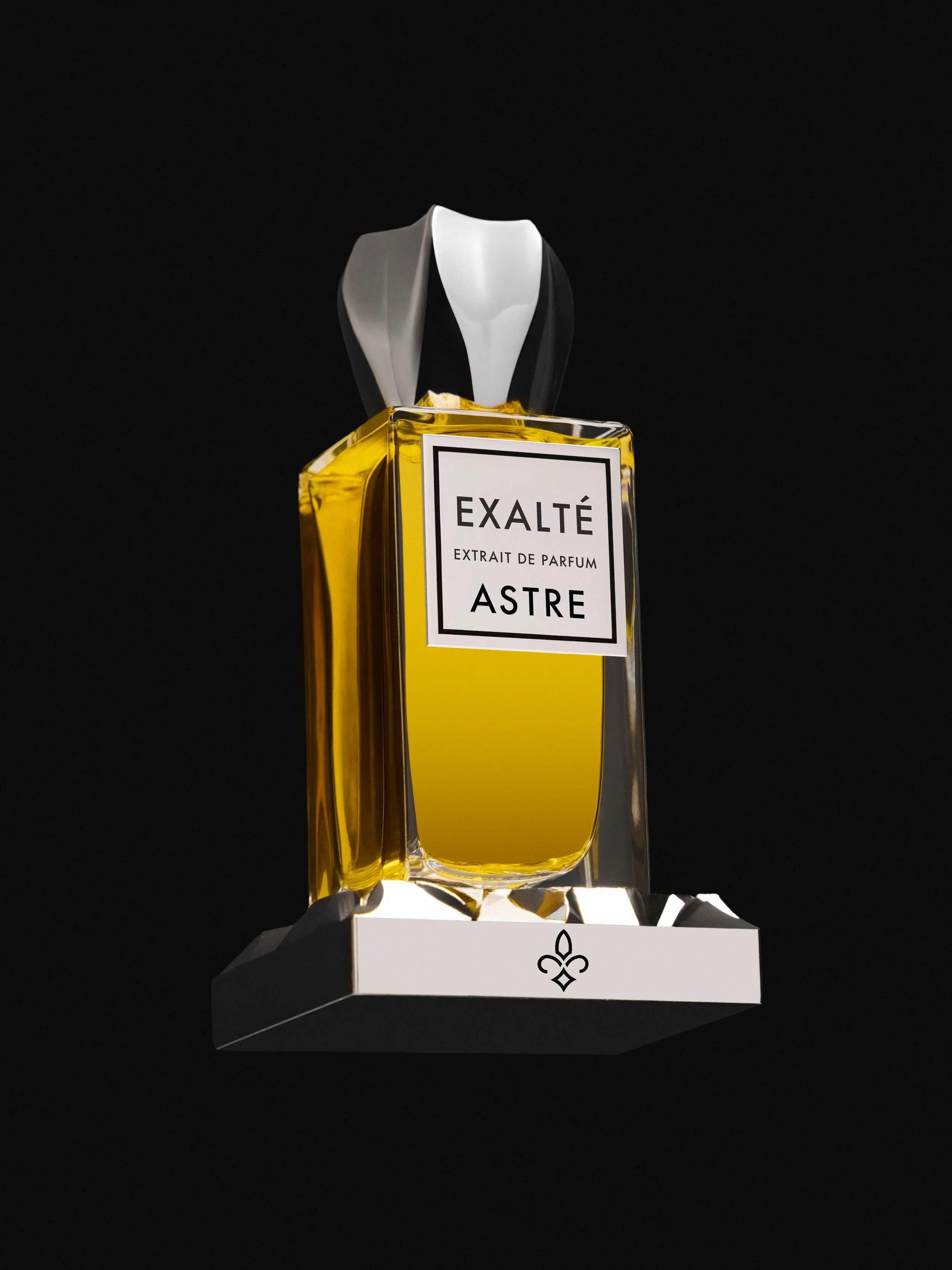 A perfume bottle labeled EXALTE ASTRE with a black, white, and gray cap, placed on a white stand against a black background.