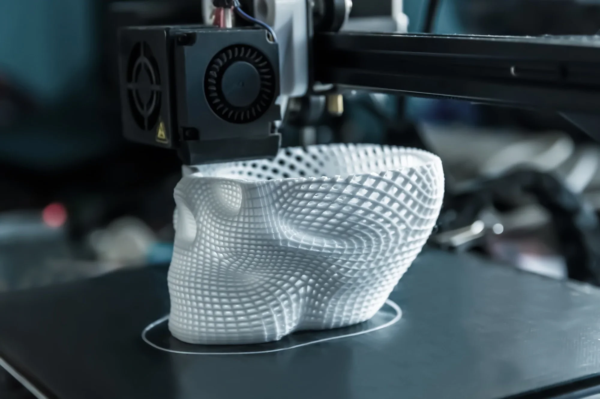 A 3D printer printing a white lattice-like object with a complex geometric pattern.