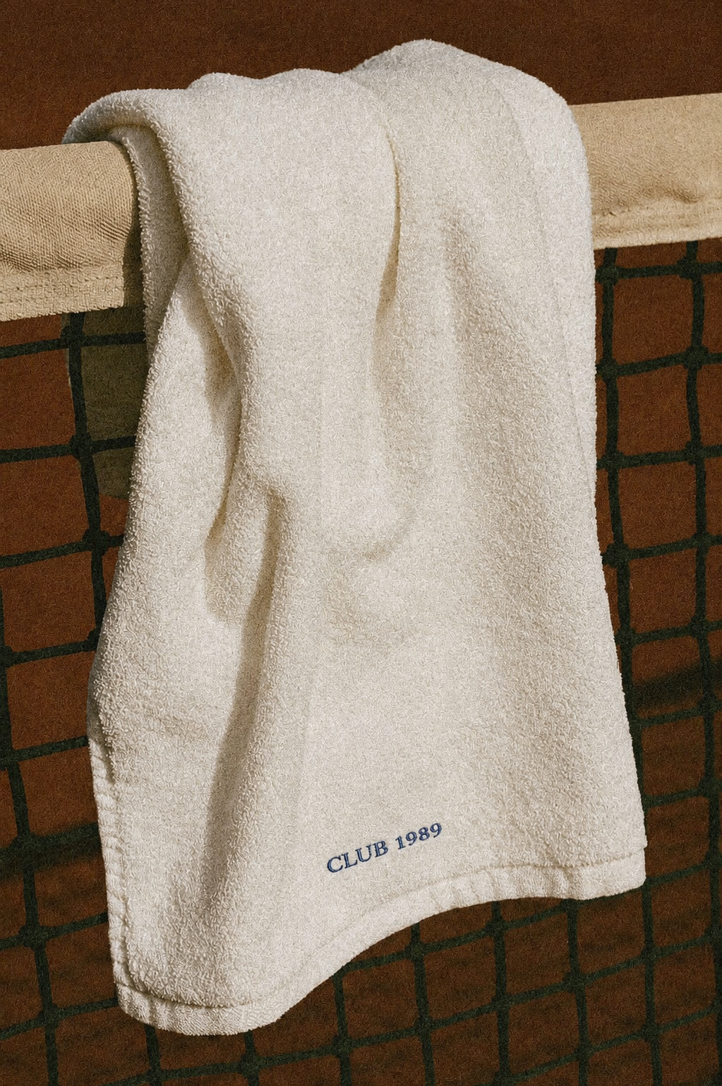 A white towel hanging on a rack with the words 'CLUB 1989' embroidered near the bottom.