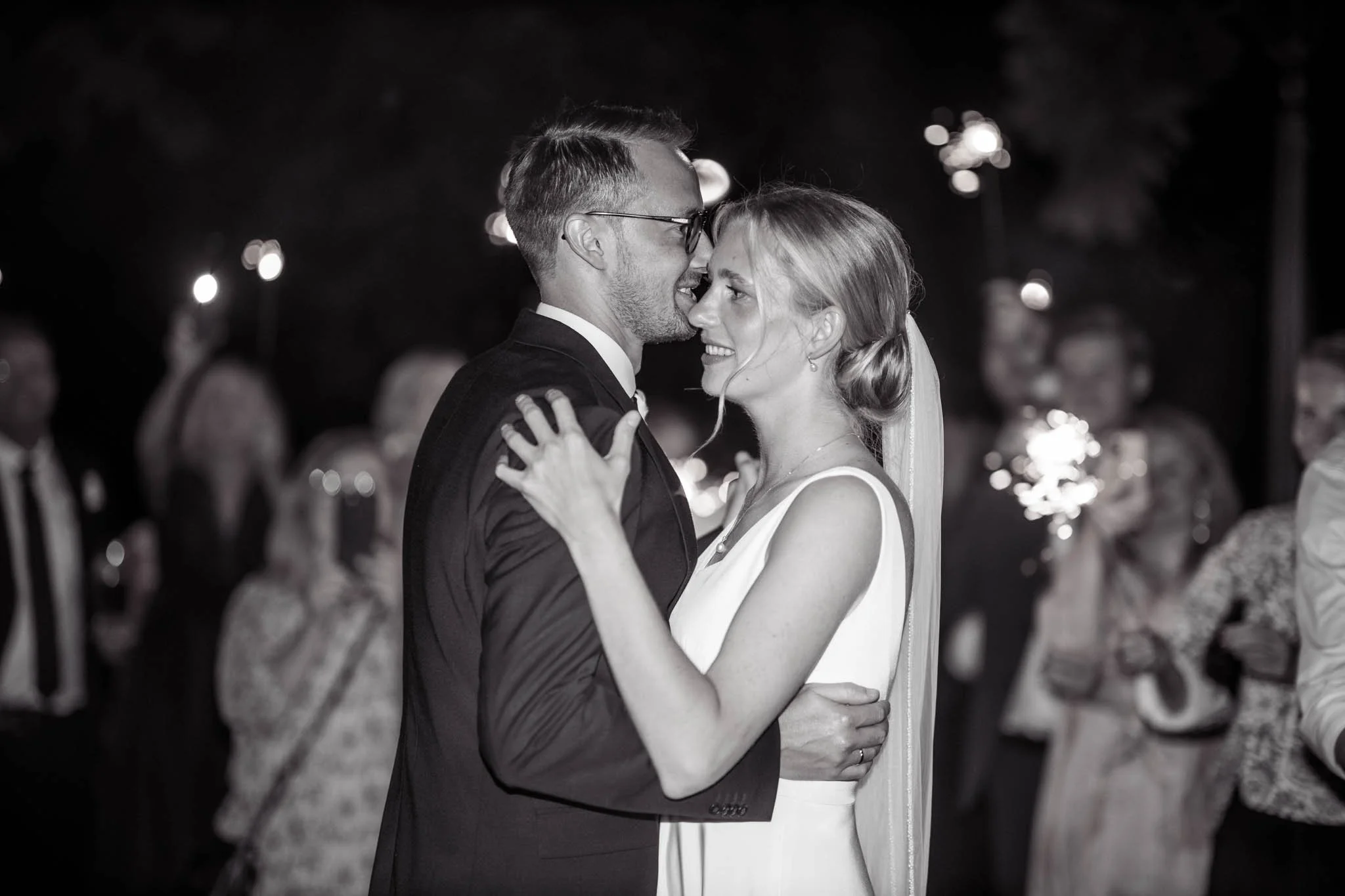 Et par i formelle beklædning danser tæt sammen, smiler og ser lykkelige ud, under en festlig aften.