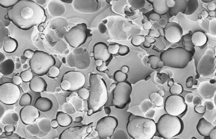 Microscope image of magnetically loaded composite material showing magnetic particles embedded in a polymer matrix.