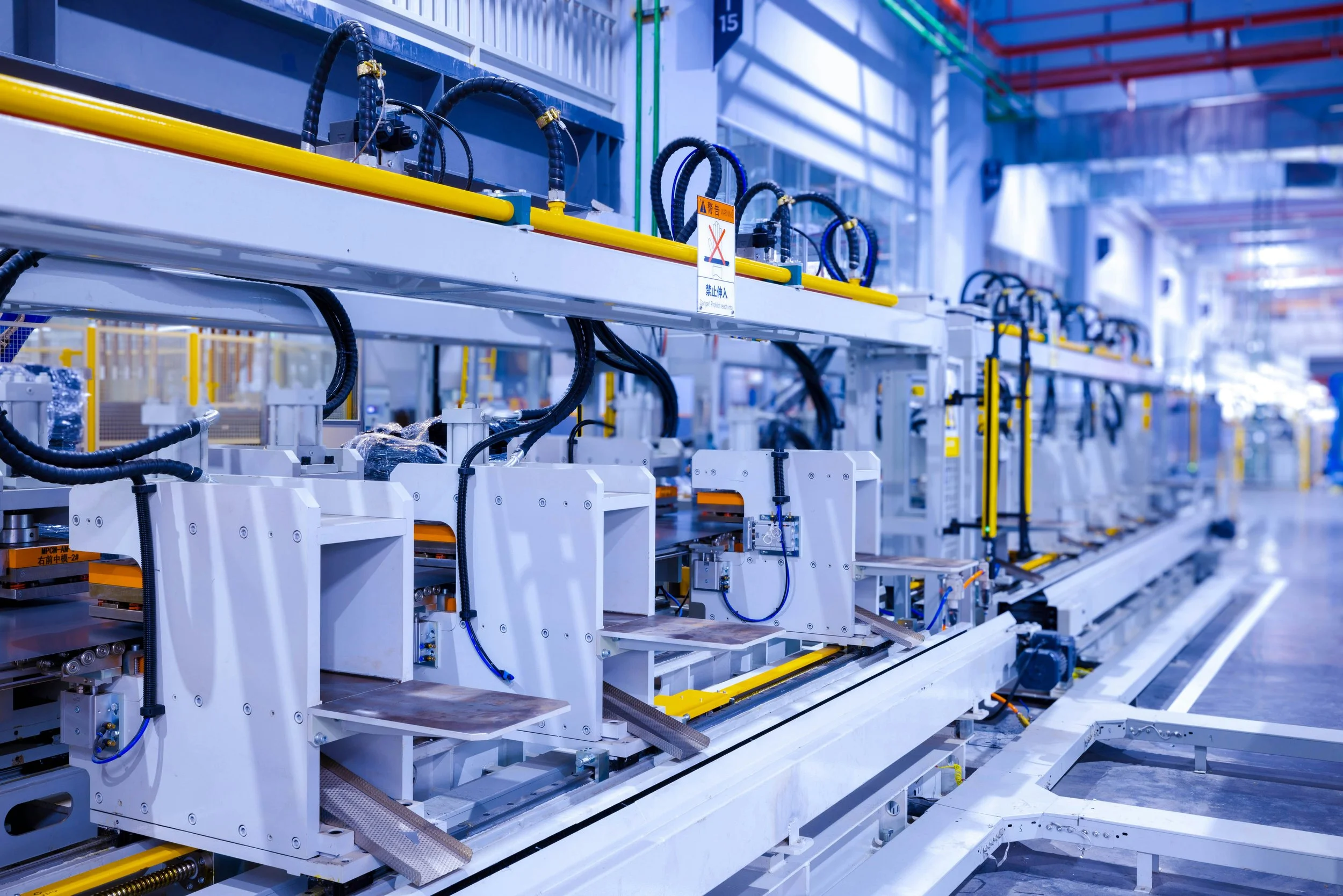 Industrial production line with motors and presses, where a flywheel sits between the grid and the load to deliver peak shaving and voltage support