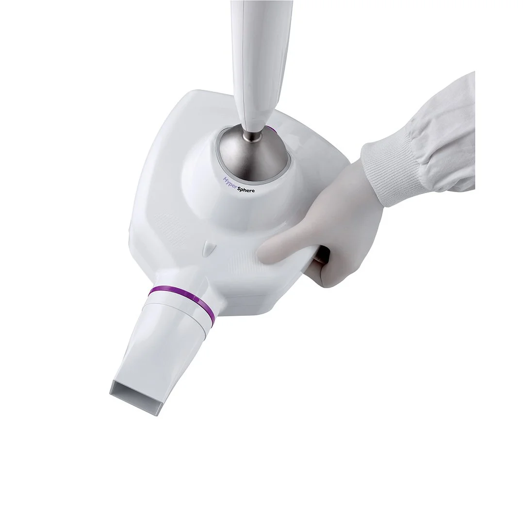 A gloved hand pressing a button on a medical or laboratory device labeled "HyperSphere" with a tube attached.