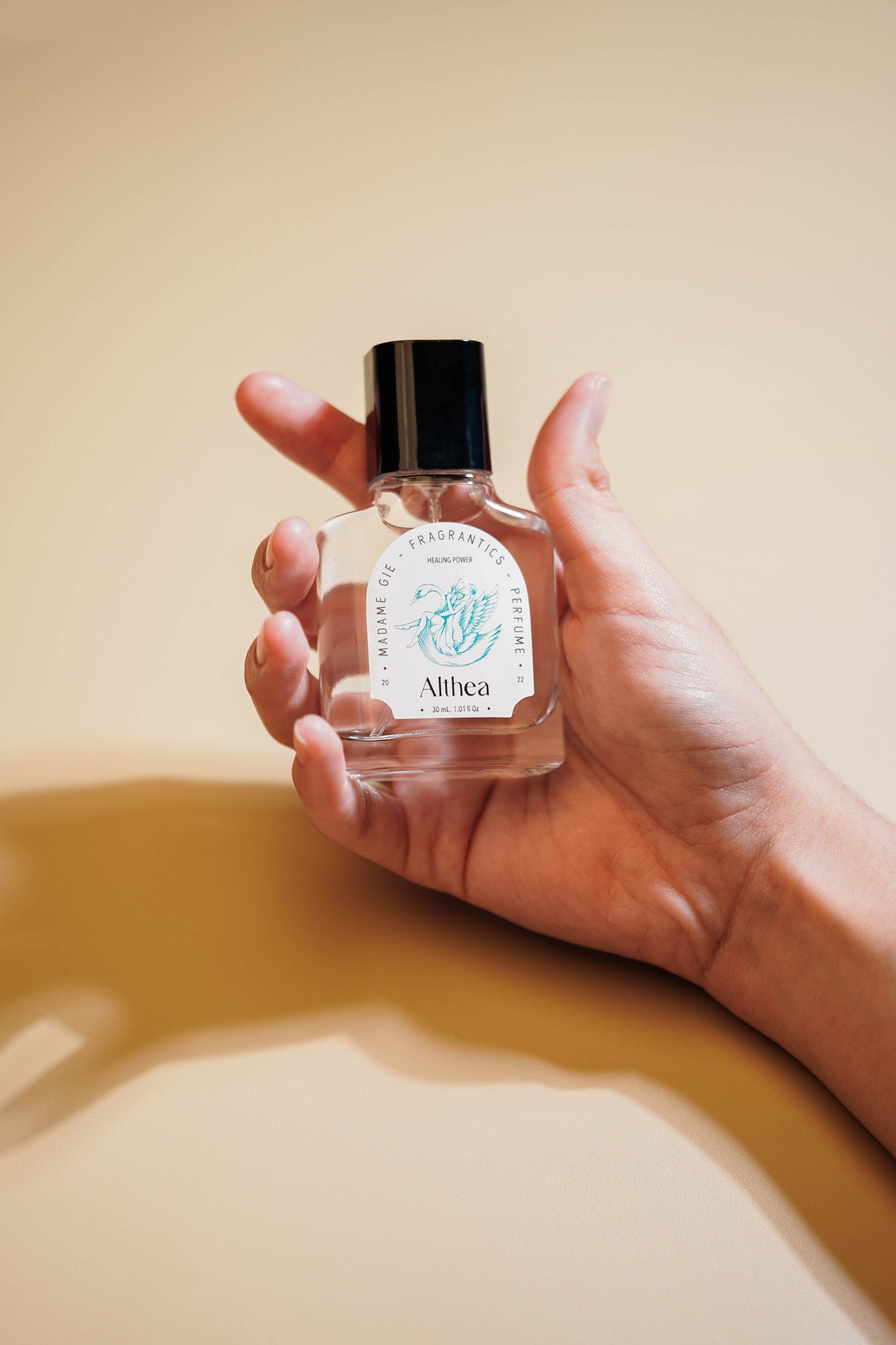 A hand showcasing a vintage glass Madame Gie perfume bottle with an elegant white label