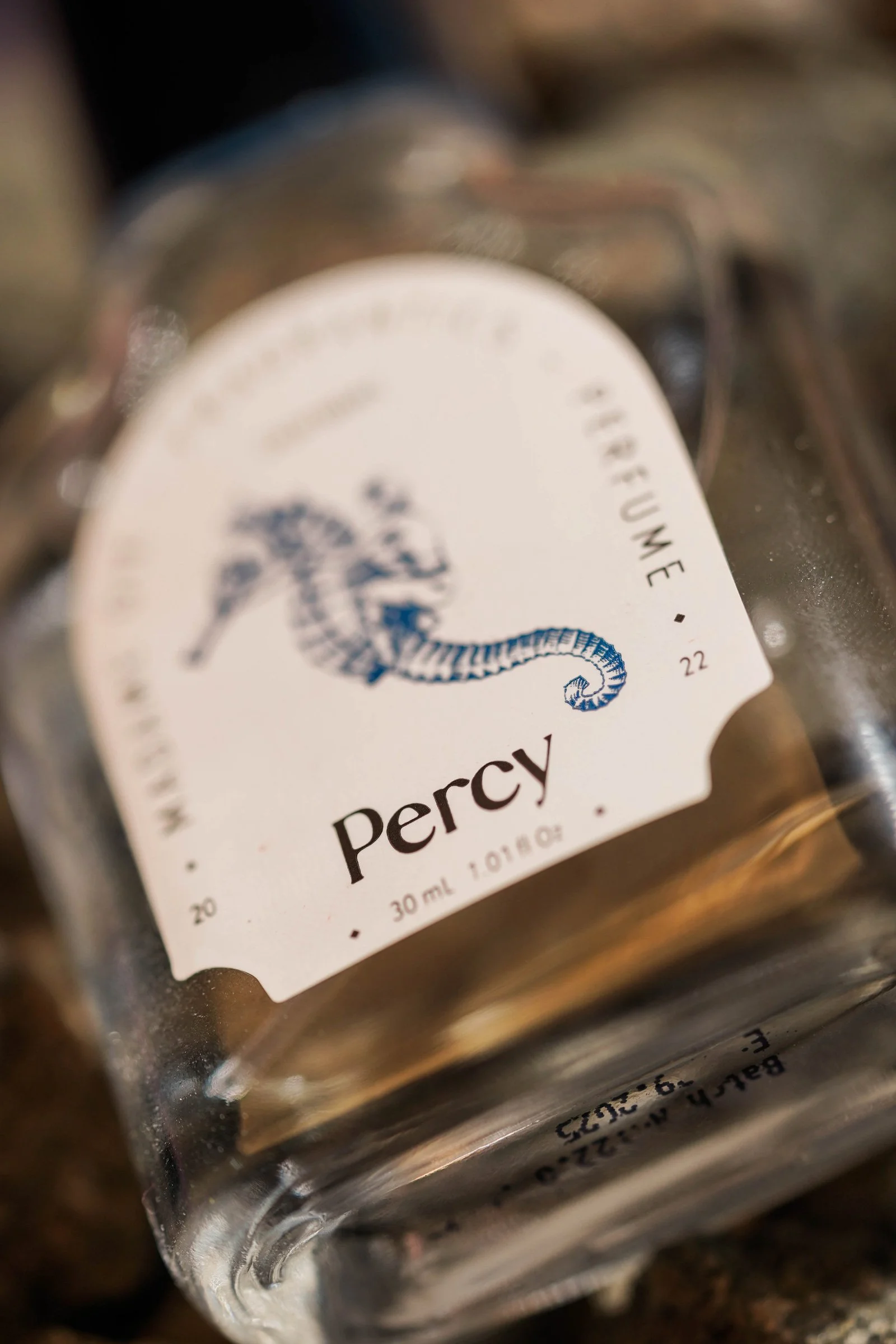 A macro close-up of the Madame Gie 'Percy' perfume bottle label showing detailed sea horse line art typography