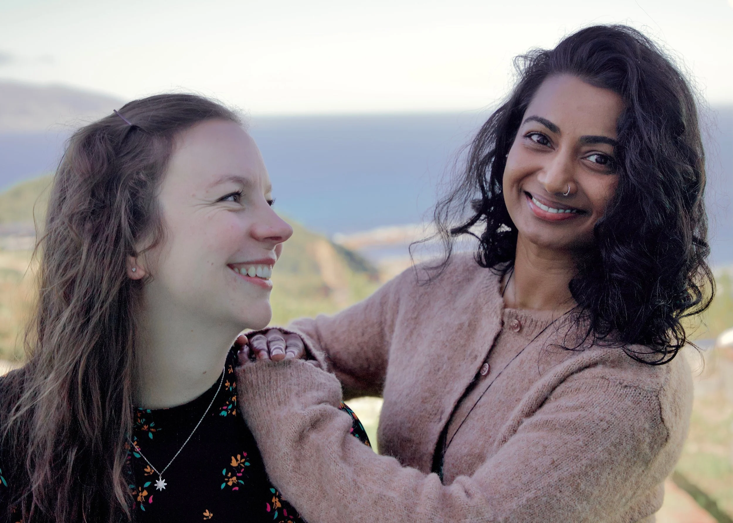Tika & Jenny, longtime friends and trusted mental health professionals in Wellington with the South Coast in the background.
