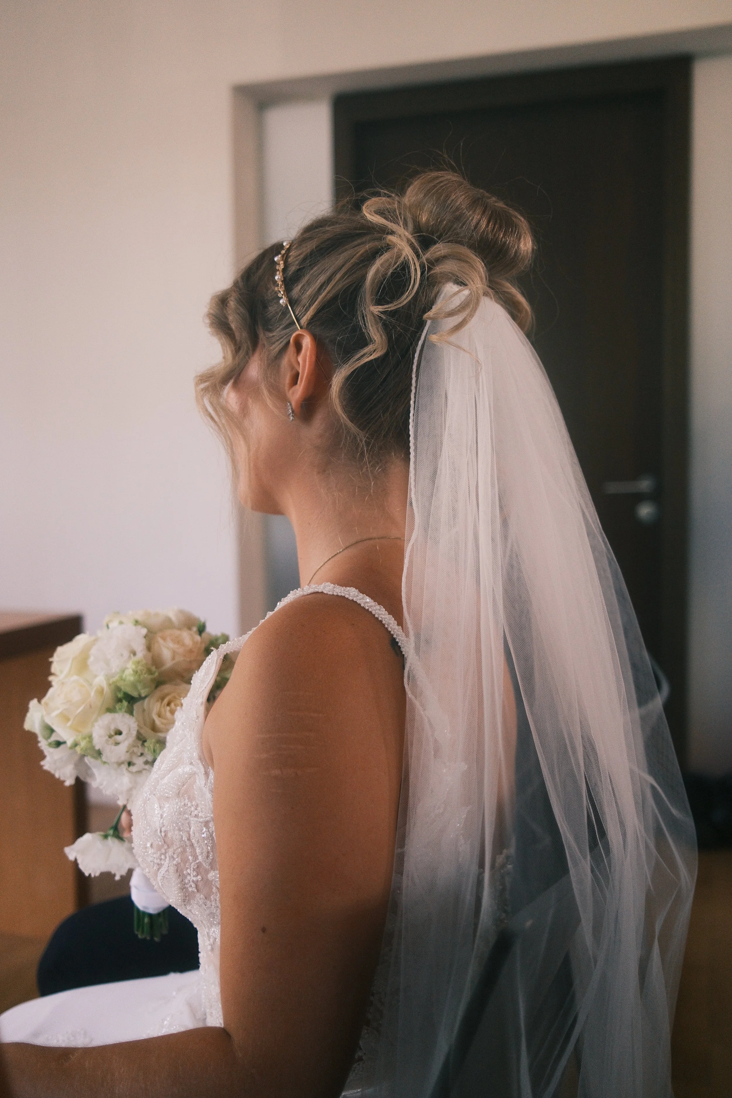 Braut im Profil von hinten mit Schleier und Hochsteckfrisur, Brautstrauß im Arm, Hochzeit in Leipzig