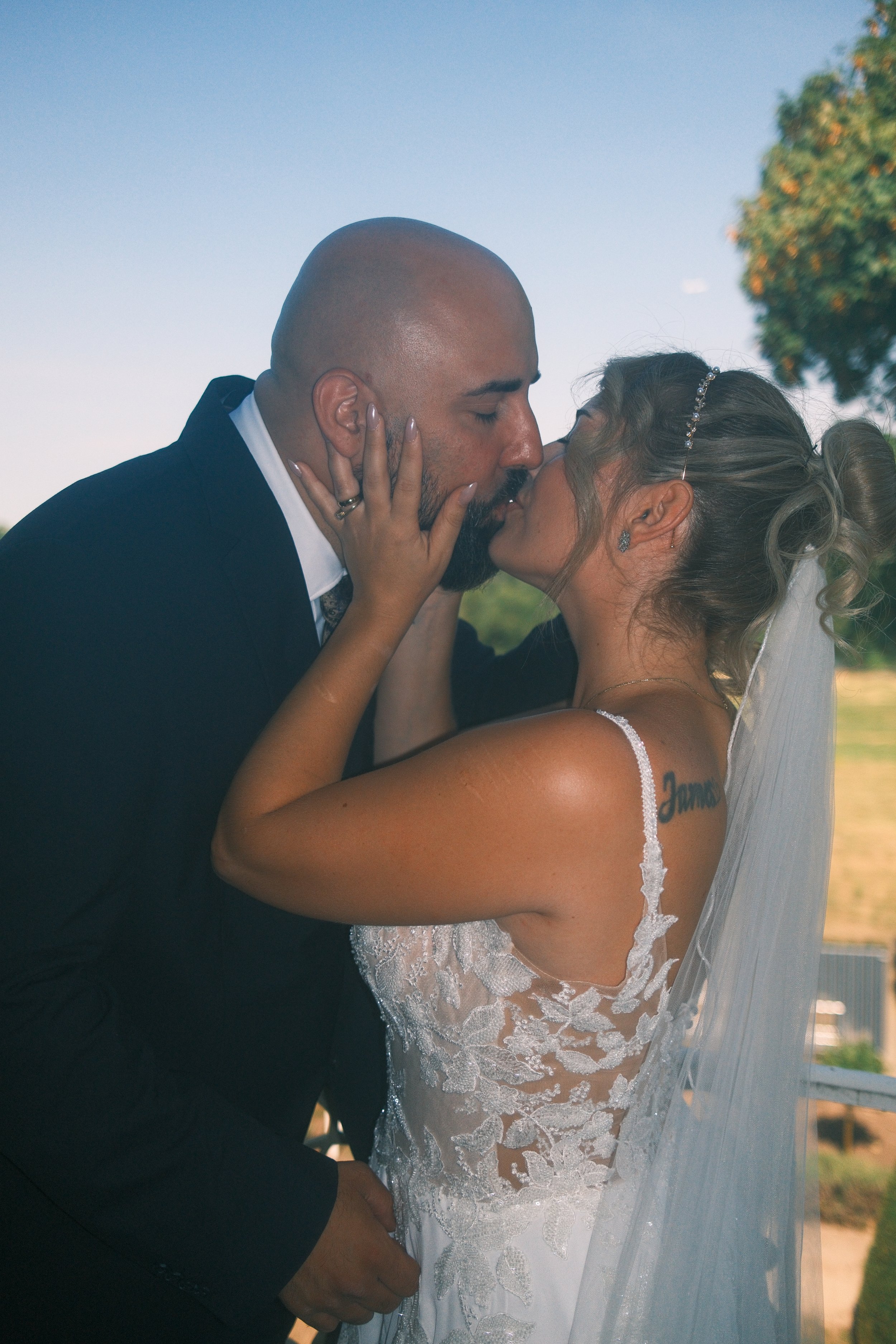 Brautpaar küsst sich im Freien unter blauem Himmel, Hochzeit in Leipzig